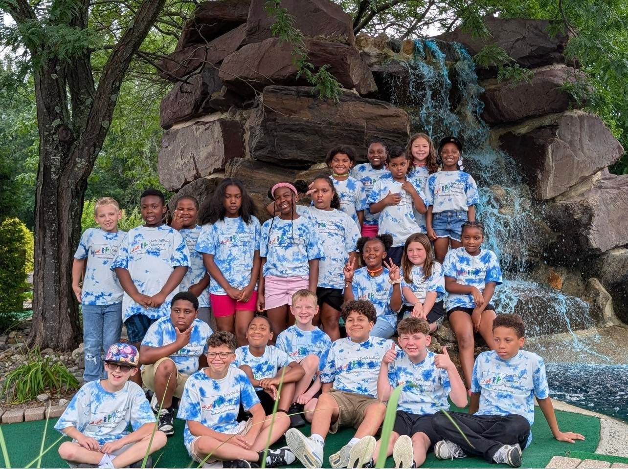 A group of children are posing for a picture in front of a waterfall.