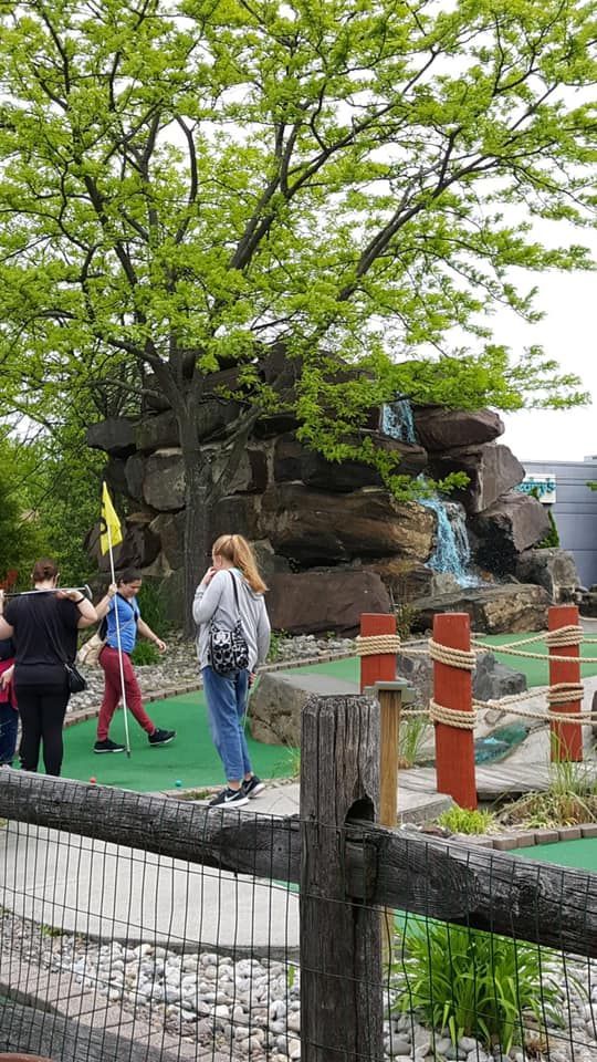 A group of people are playing mini golf in a park.