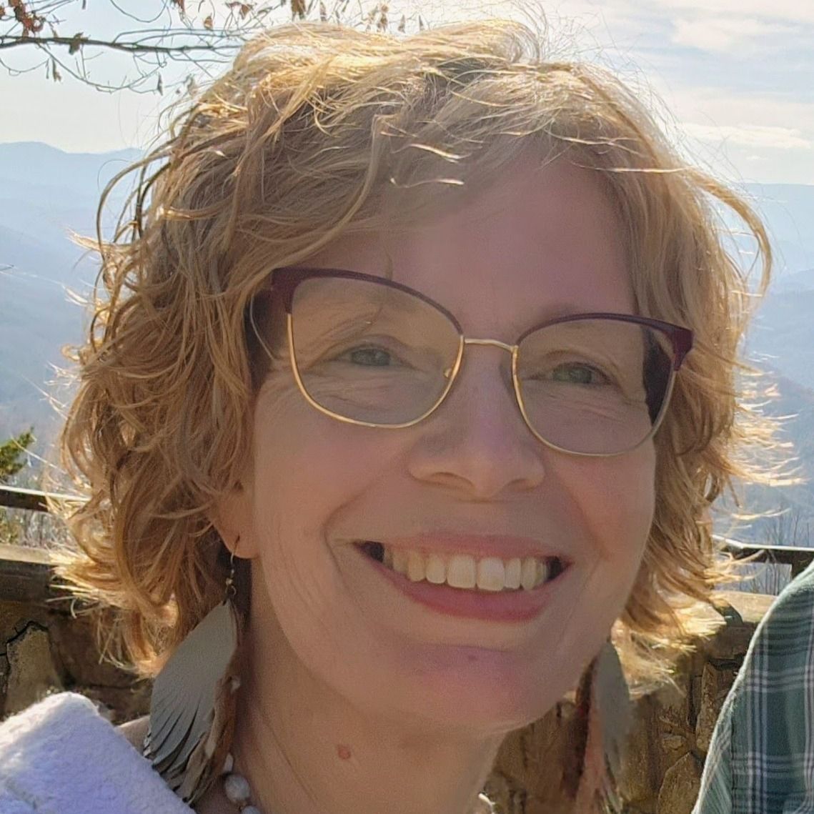 Black and white photo of a lighthouse on a rocky hill under a cloudy sky.