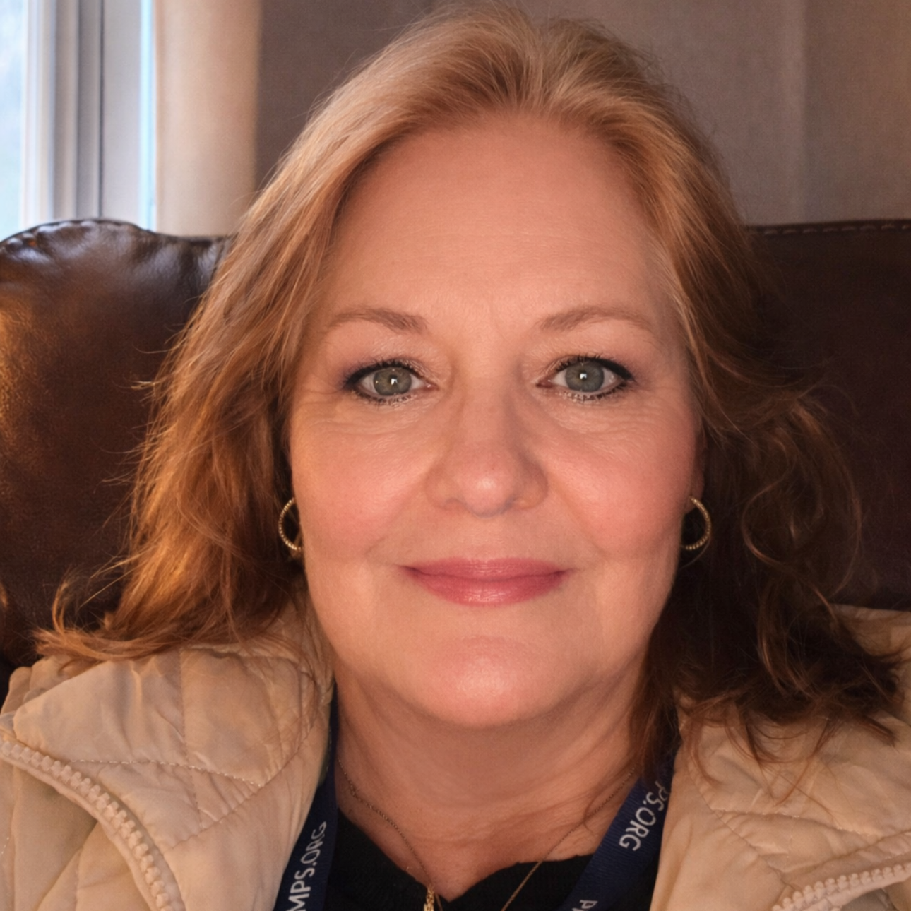 Waterfall cascading down a rocky hillside into a stream, surrounded by lush green foliage and large boulders.