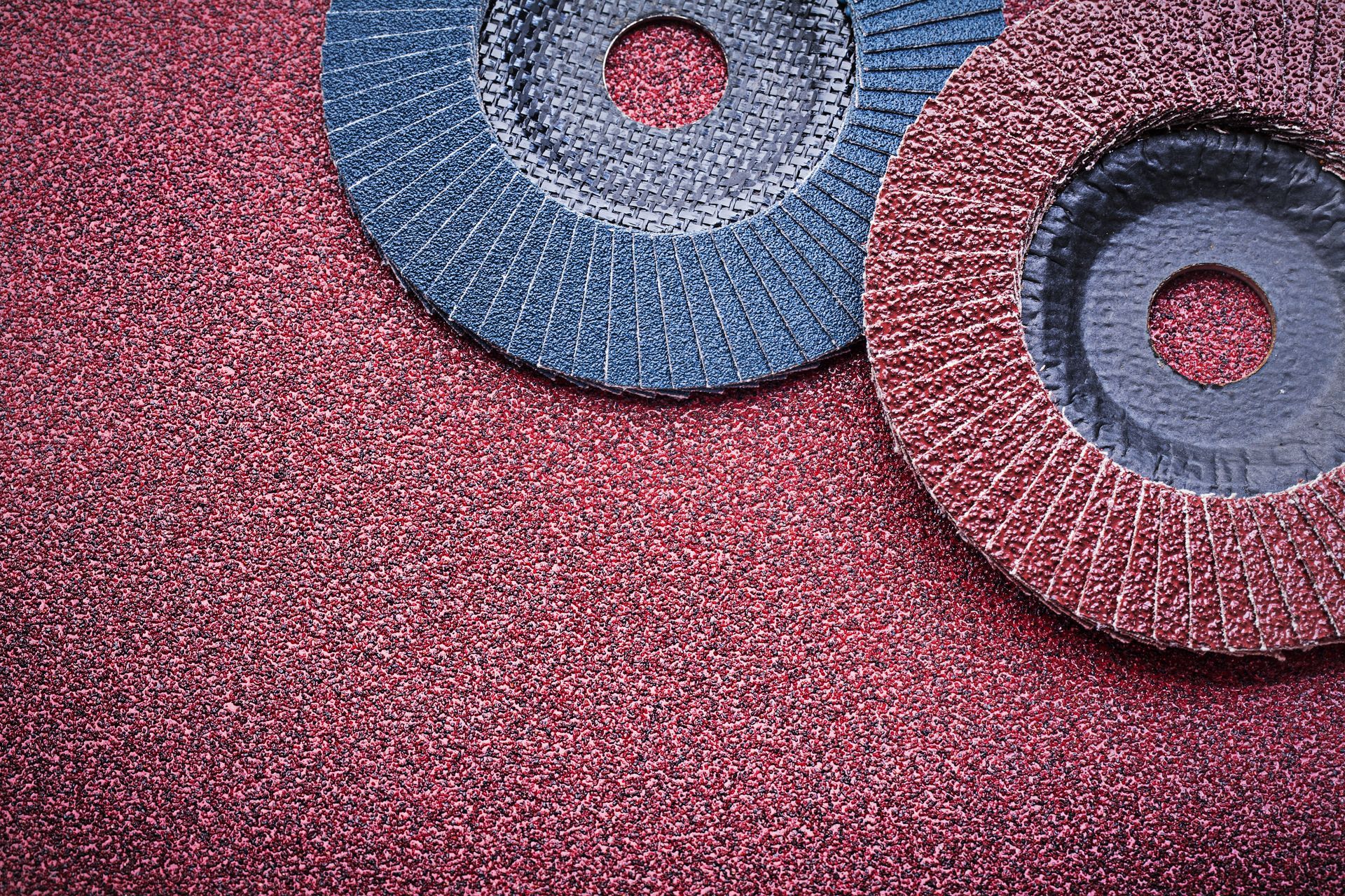 Due dischi abrasivi sono posizionati sopra una superficie rossa.