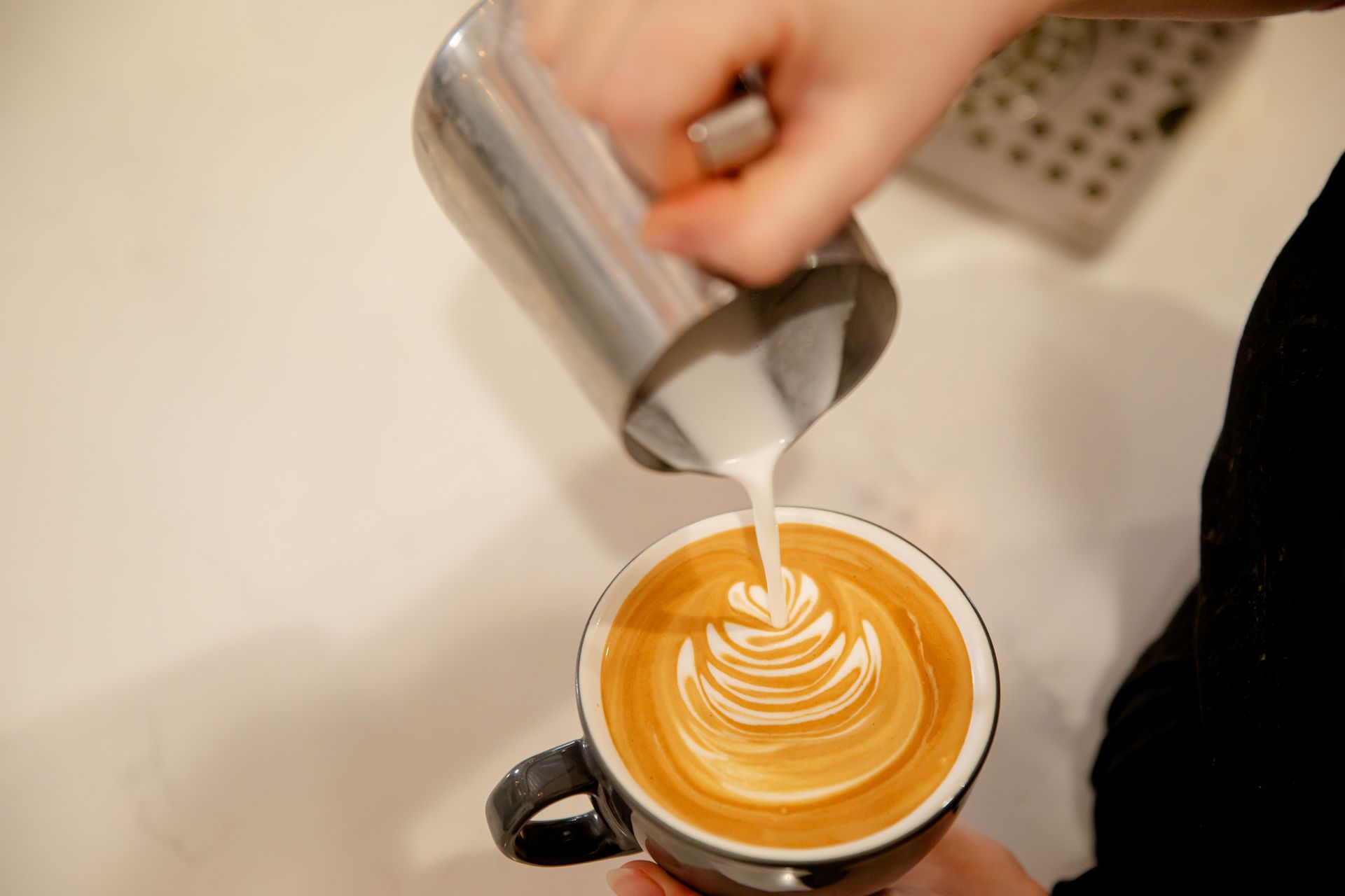 A person is pouring milk into a cup of coffee