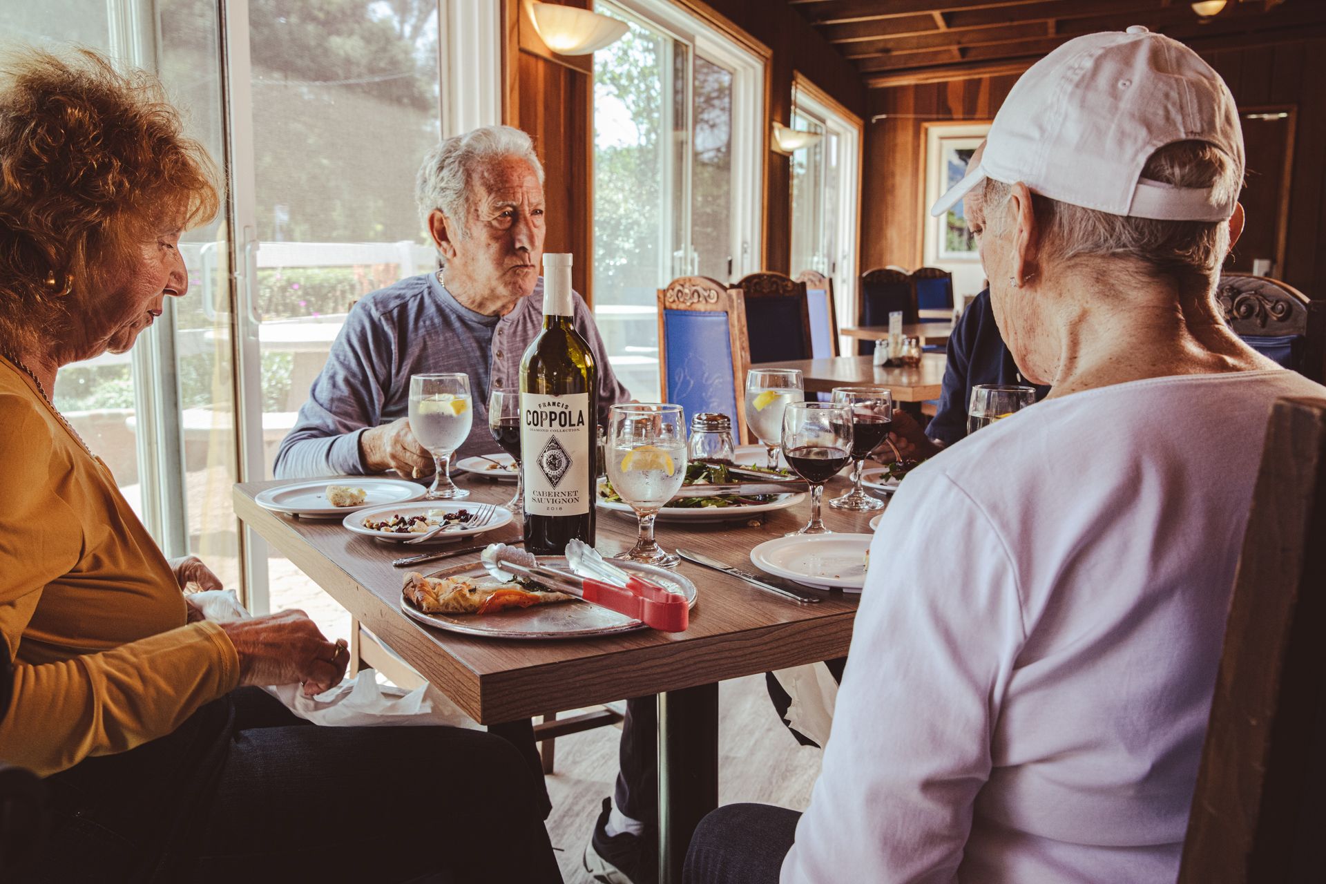 A group of people are sitting at a table with a bottle of wine on it