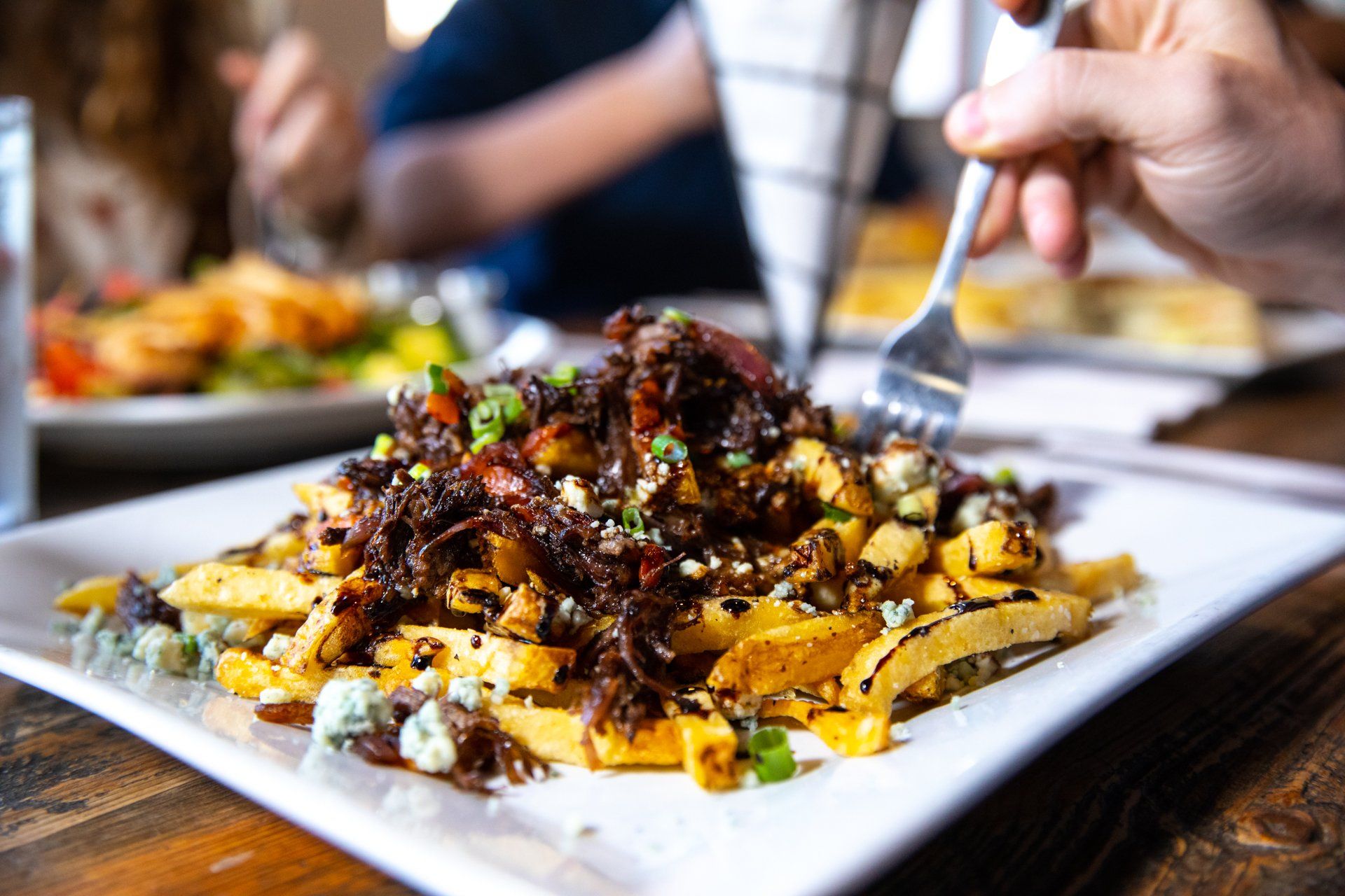 A person is eating french fries with a fork