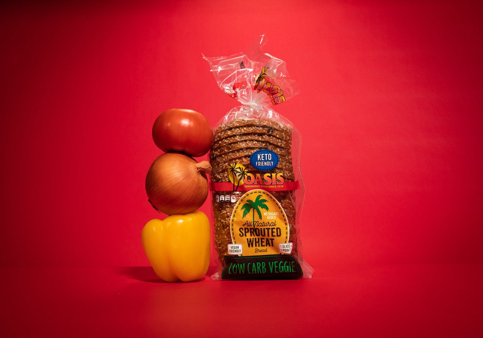 A bag of bread sits next to vegetables on a red background