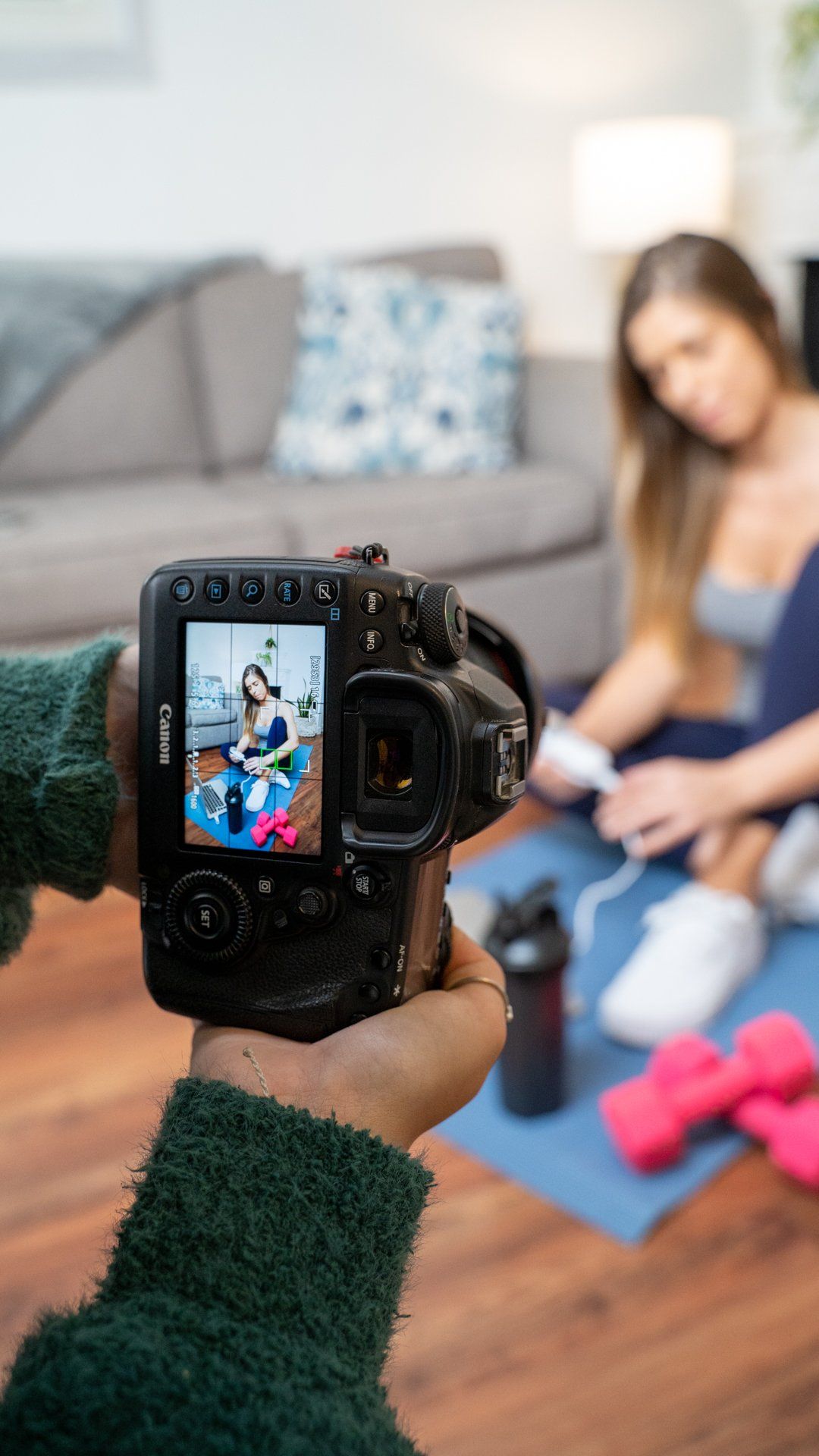 A person is taking a picture of a woman on a yoga mat