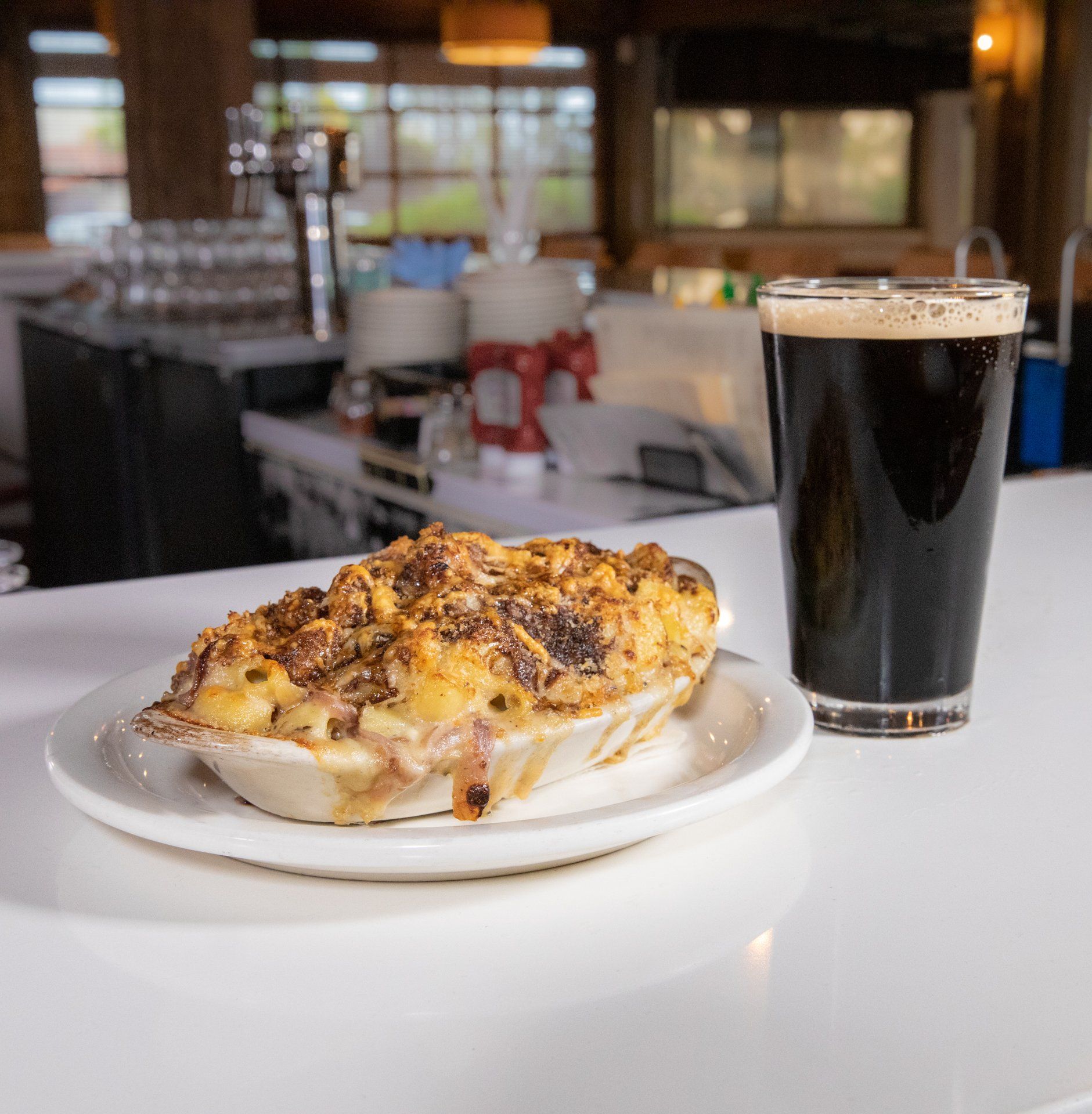A plate of macaroni and cheese next to a glass of beer