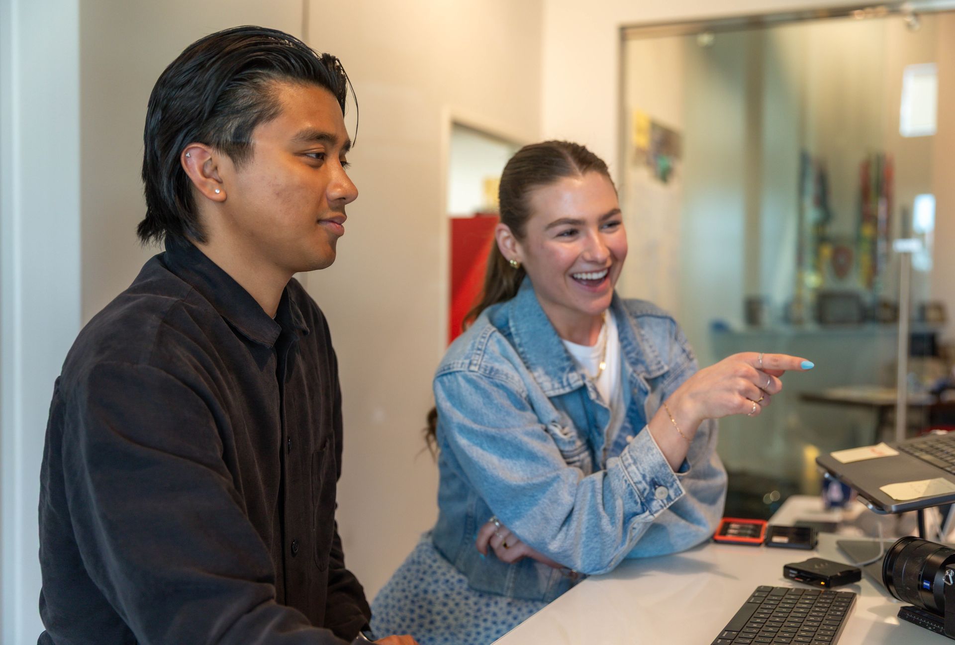 A woman is sitting at a desk talking on a cell phone.
