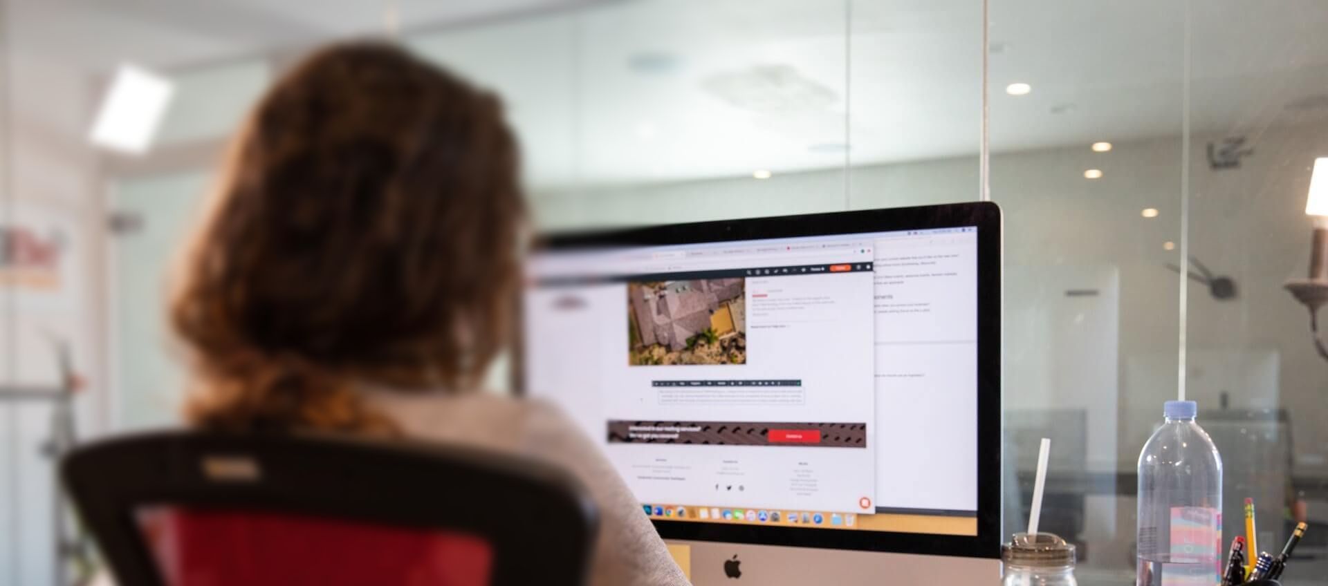 A woman sits in front of an apple computer