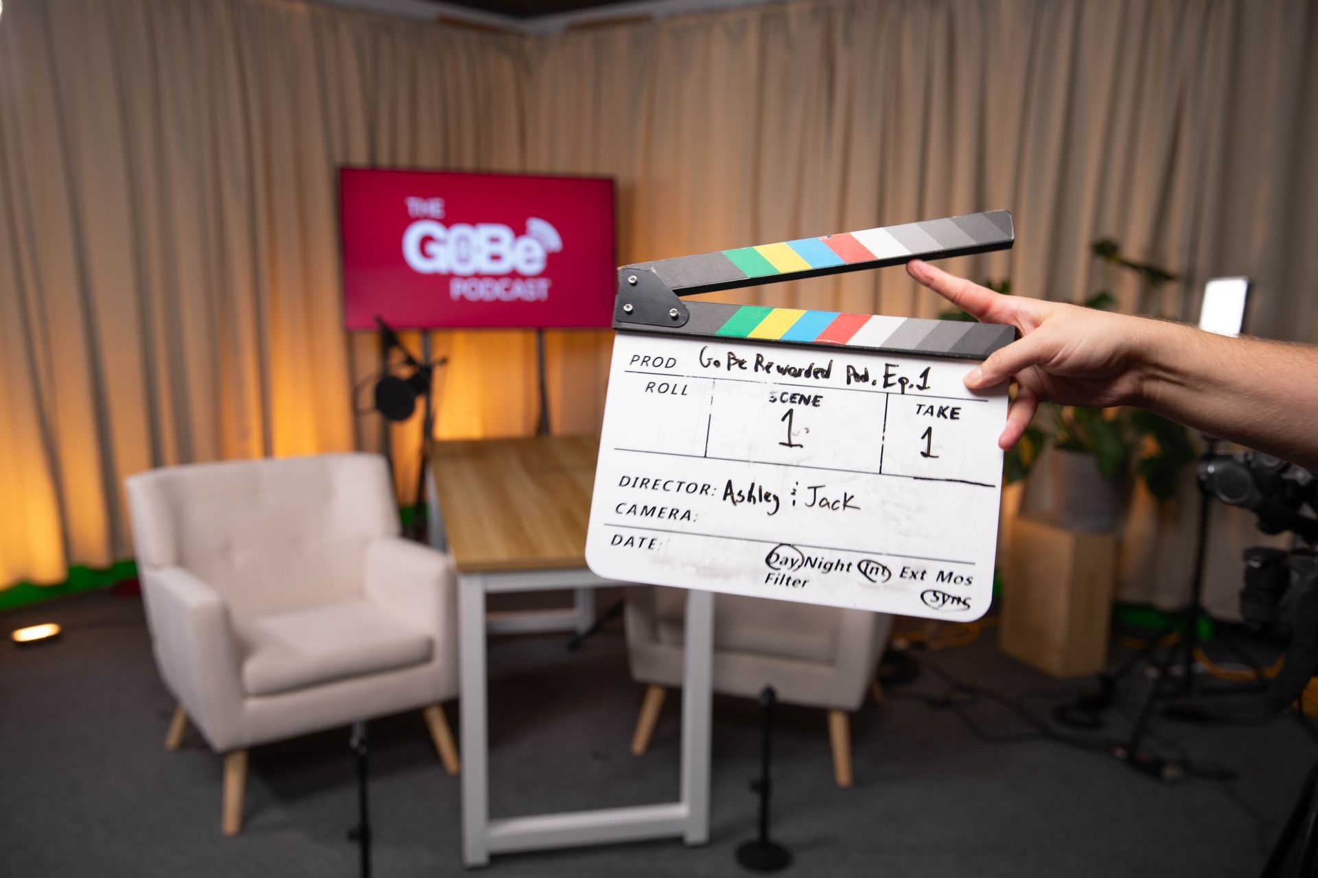 A person is holding a clapper board in front of a gobo logo