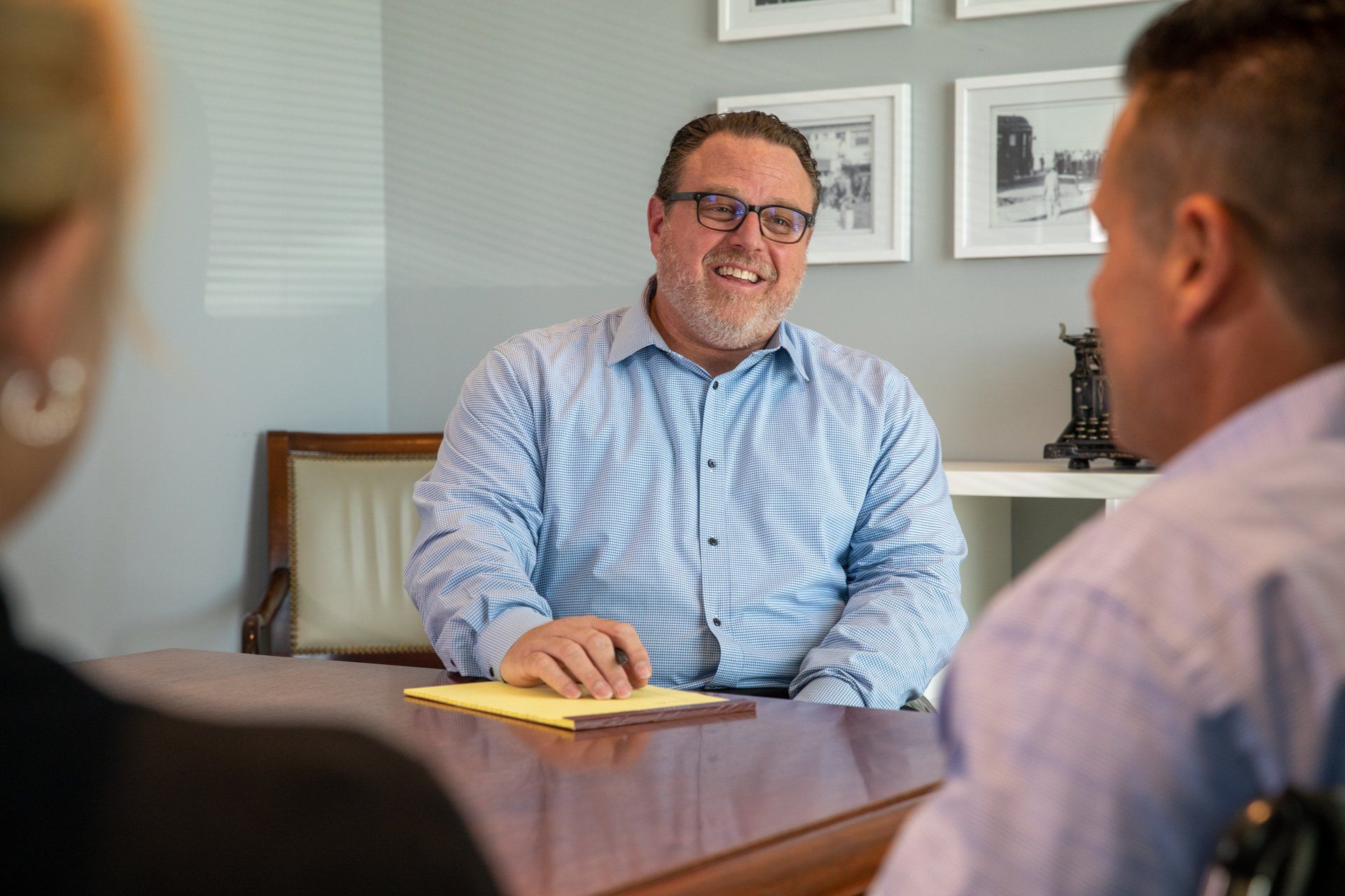 A man with glasses is sitting at a table with two other people