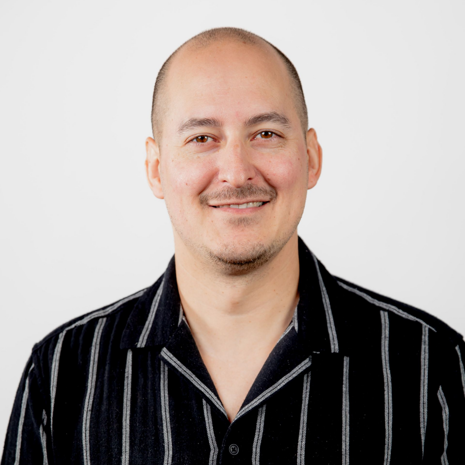 A man with a tattoo on his arm is wearing a black and white striped shirt