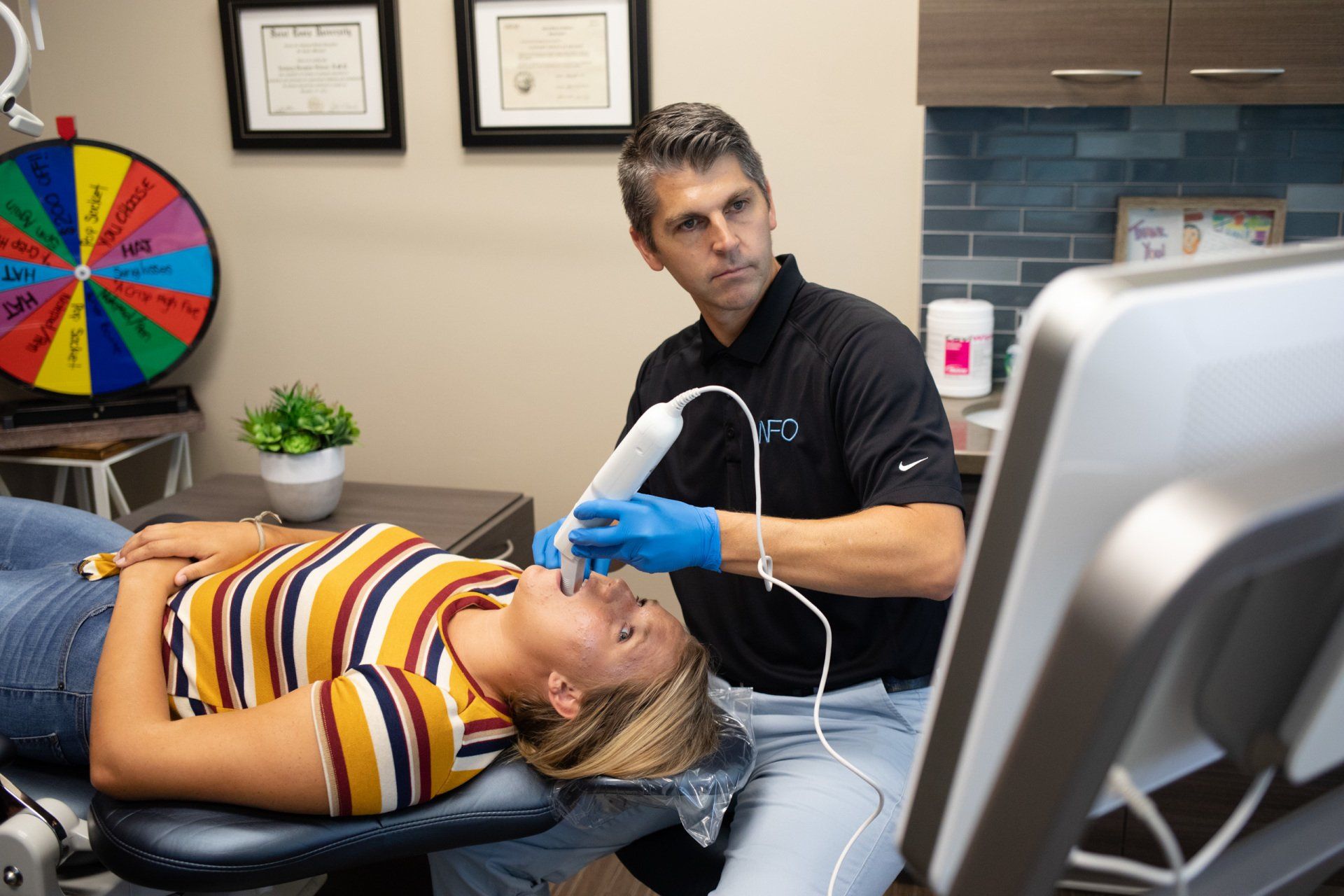 A woman is laying in a dental chair while a man is using a machine