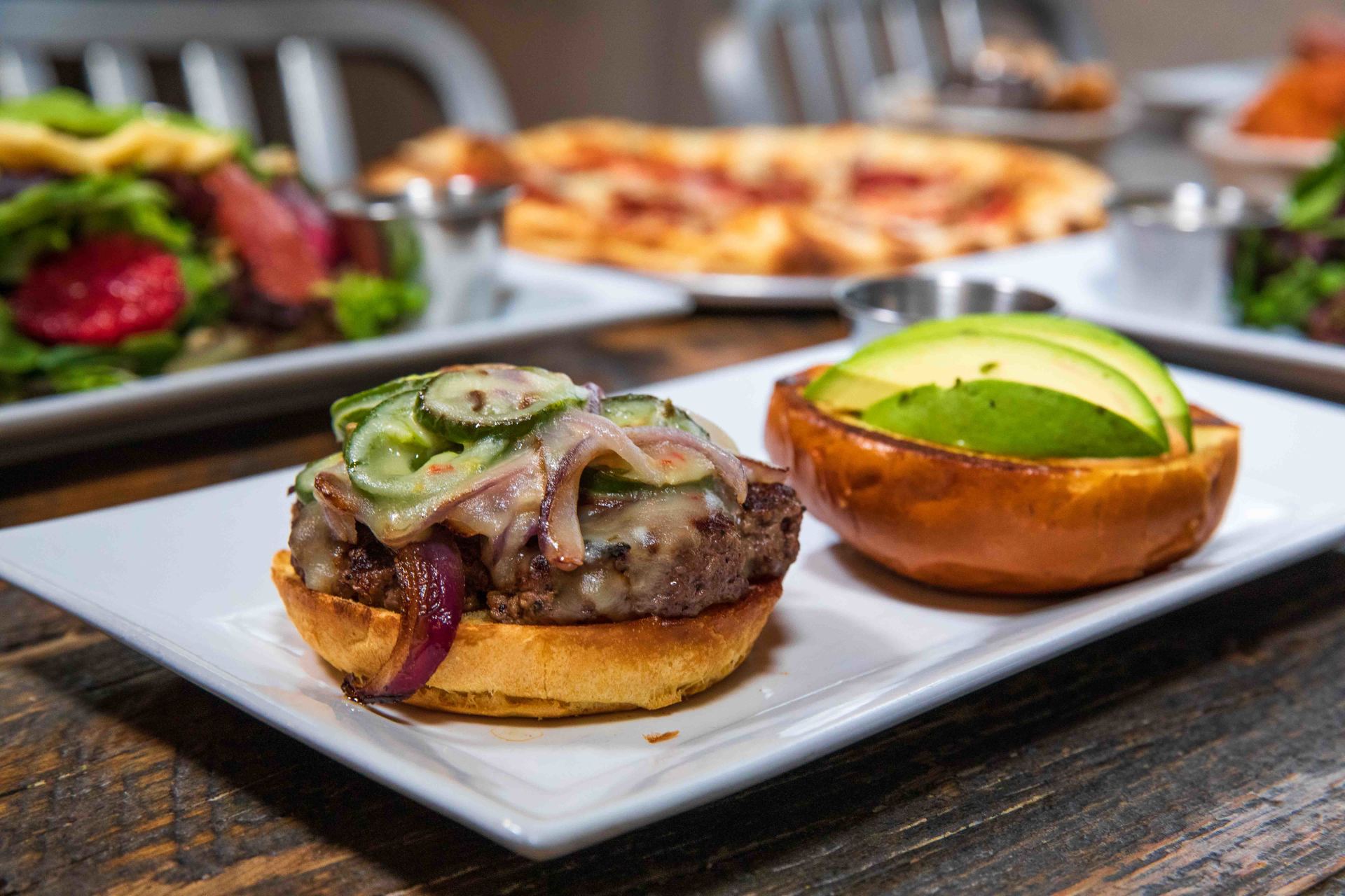 A white plate topped with a hamburger and avocado