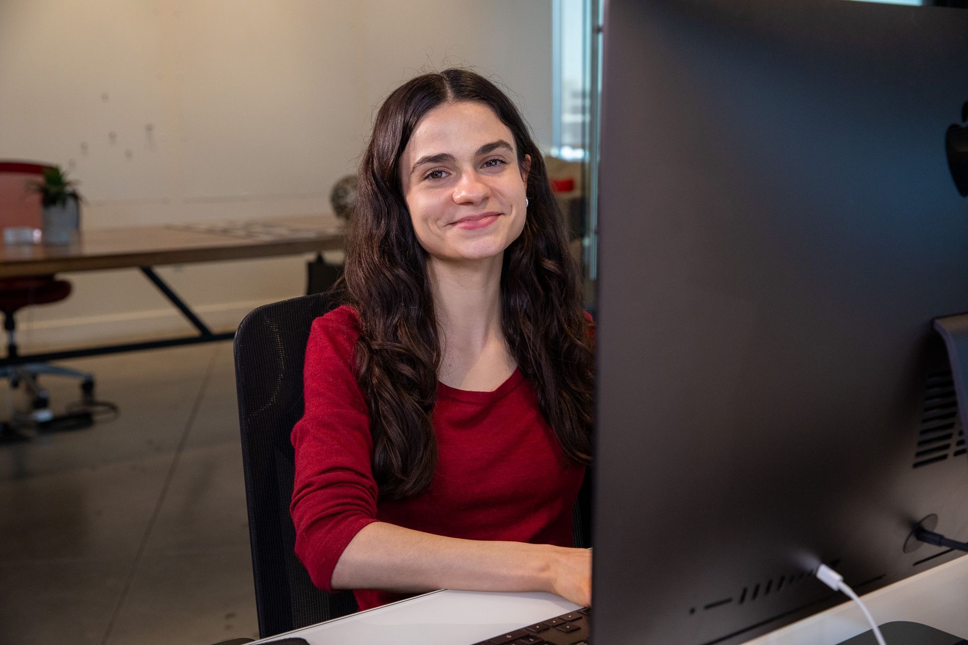 A woman sitting at a desk pointing at a computer screen
