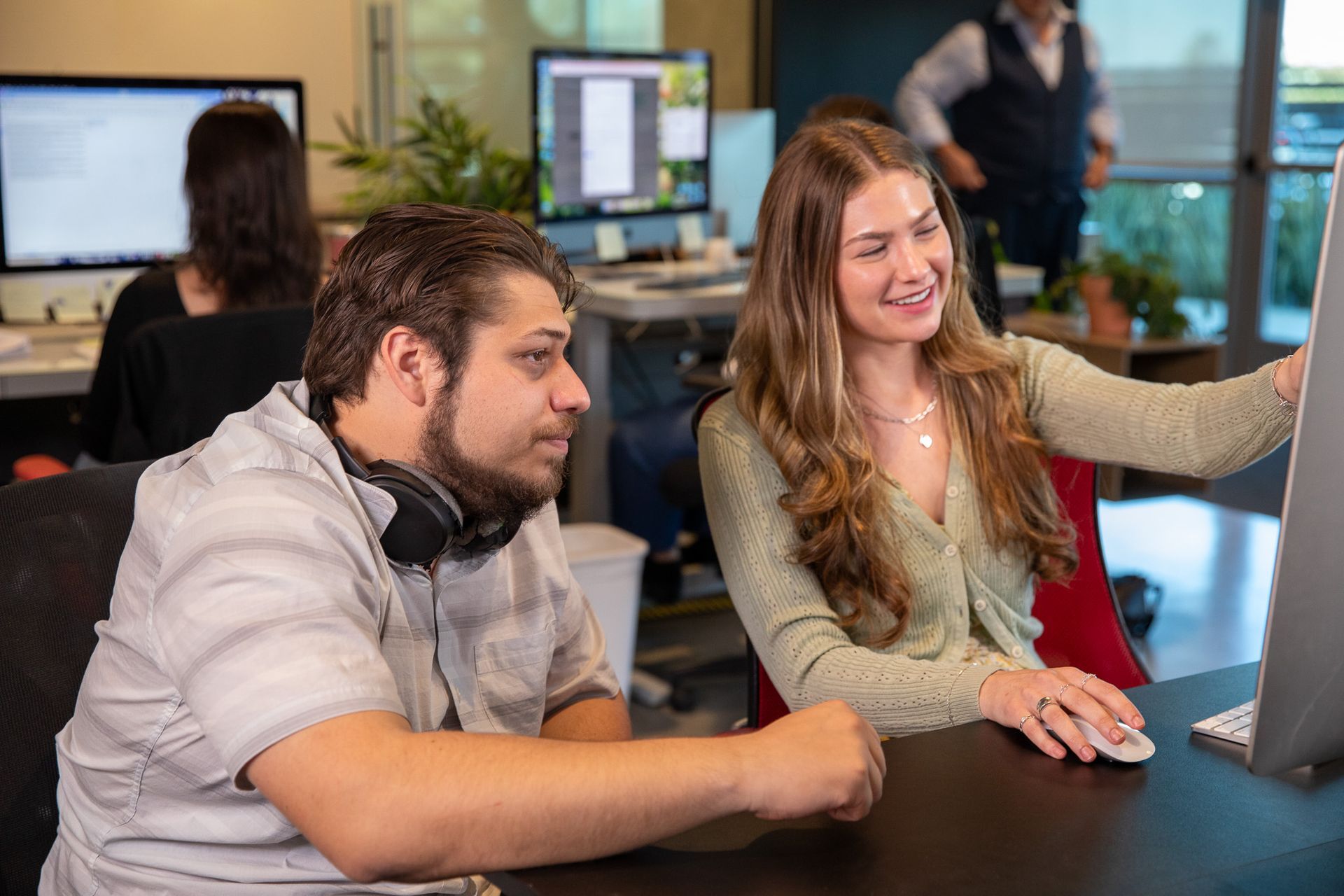 A woman is sitting at a desk using an apple computer