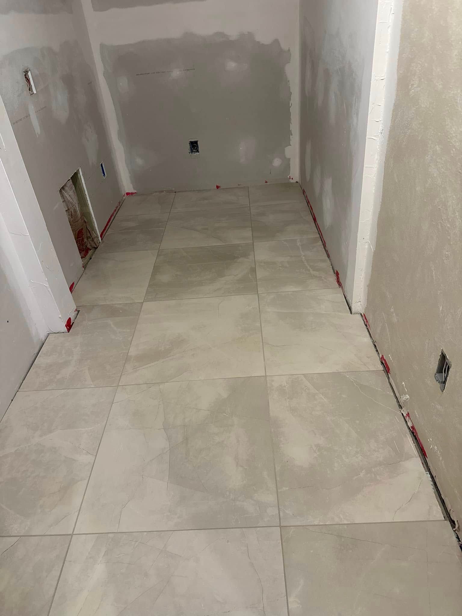 An unfinished room with a light gray tiled floor and unpainted drywall walls.