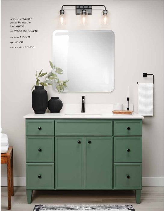 Green bathroom vanity with black accents, topped with white counter, mirror, and decor.
