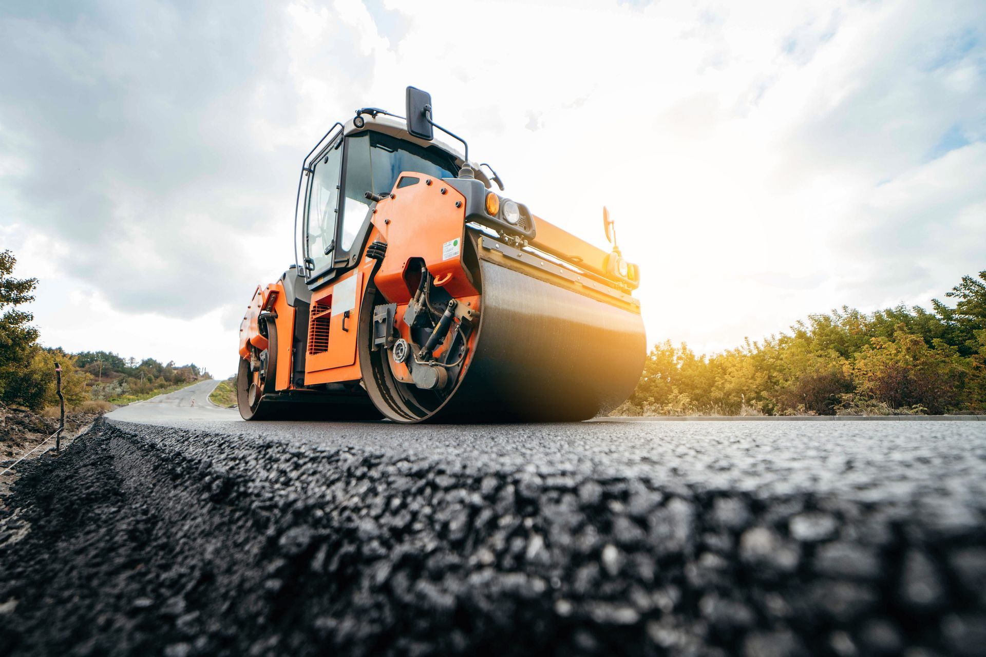 Vibratory asphalt roller compactor compacting new asphalt pavement.