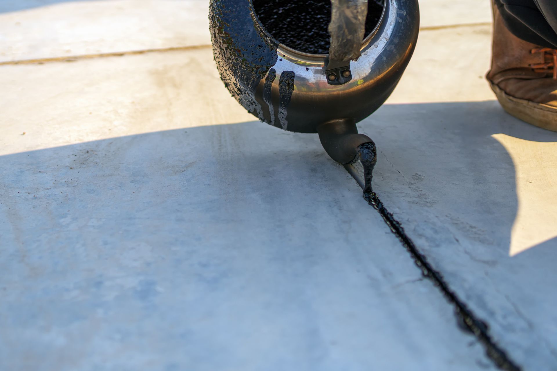 Workers pour hot asphalt on the polished cement concrete floor.