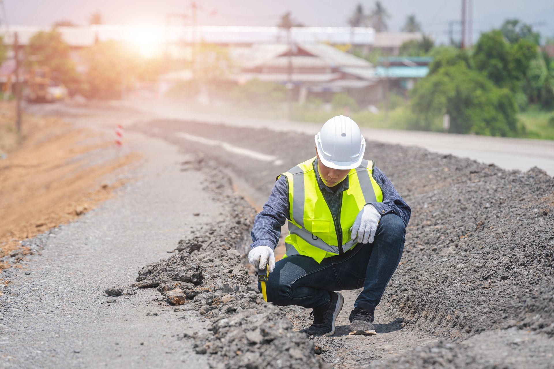 Engineer worker making measuring with equipment at construction site during road works.