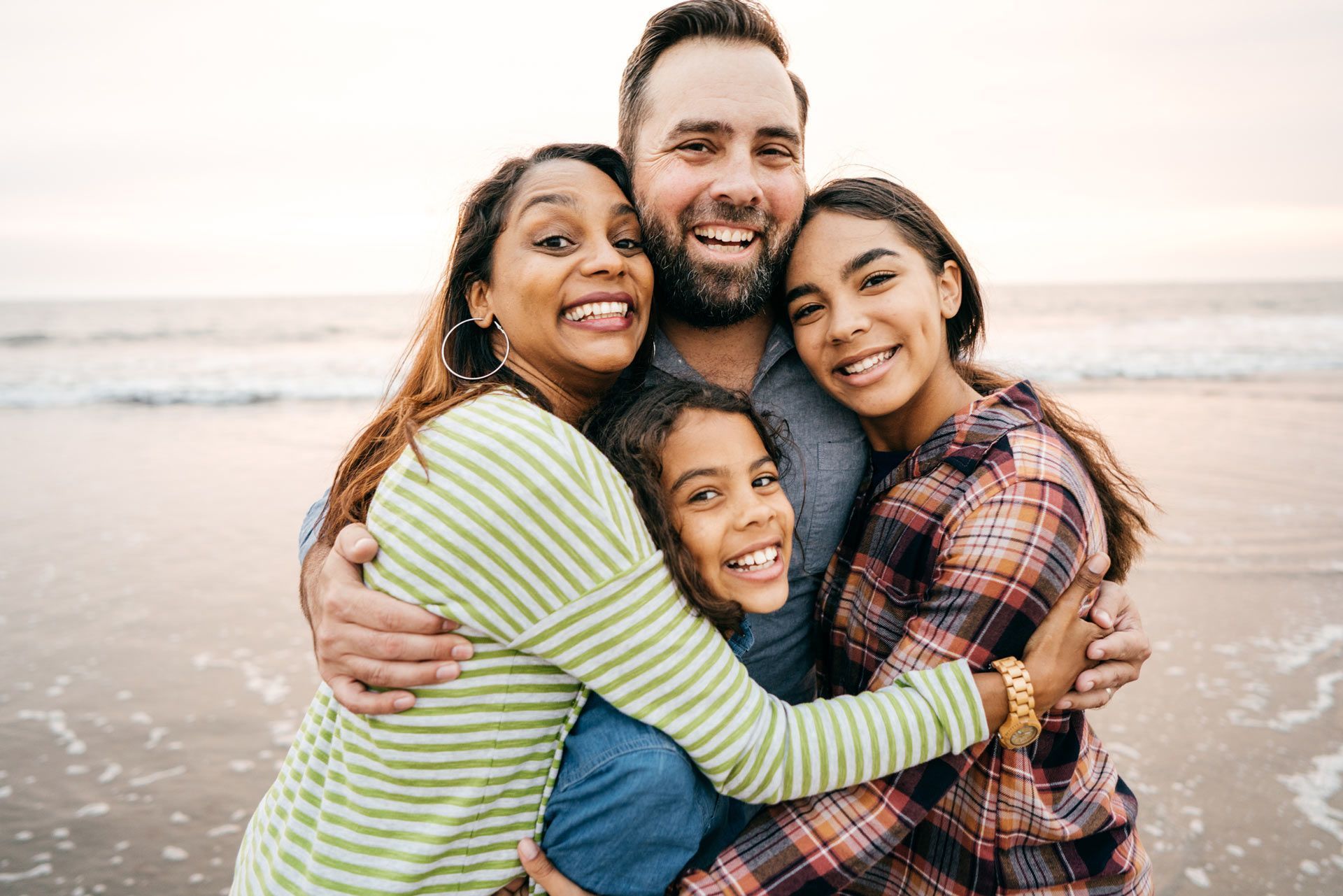 A family is hugging each other on the beach