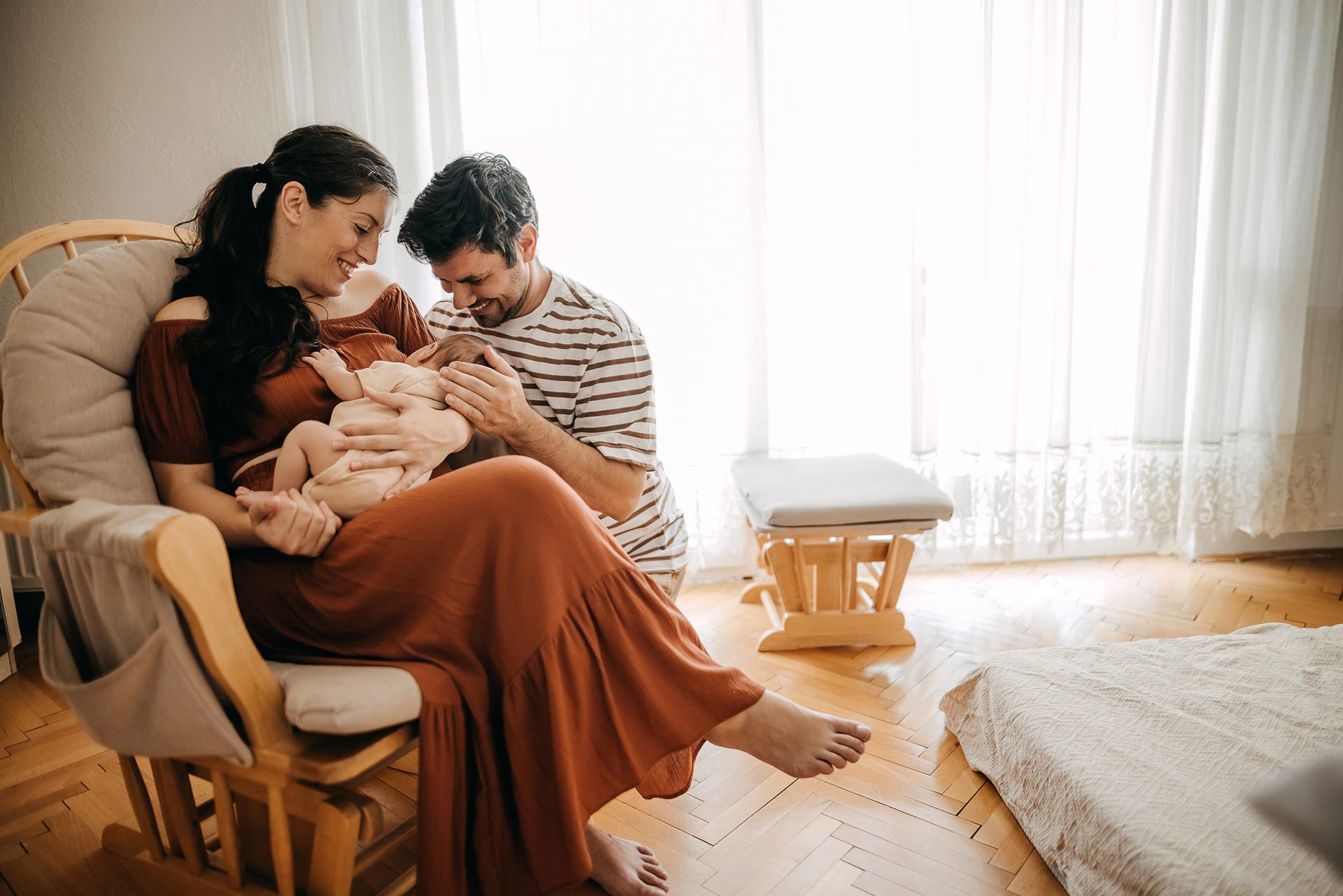 A man and a woman are sitting in a rocking chair holding a baby