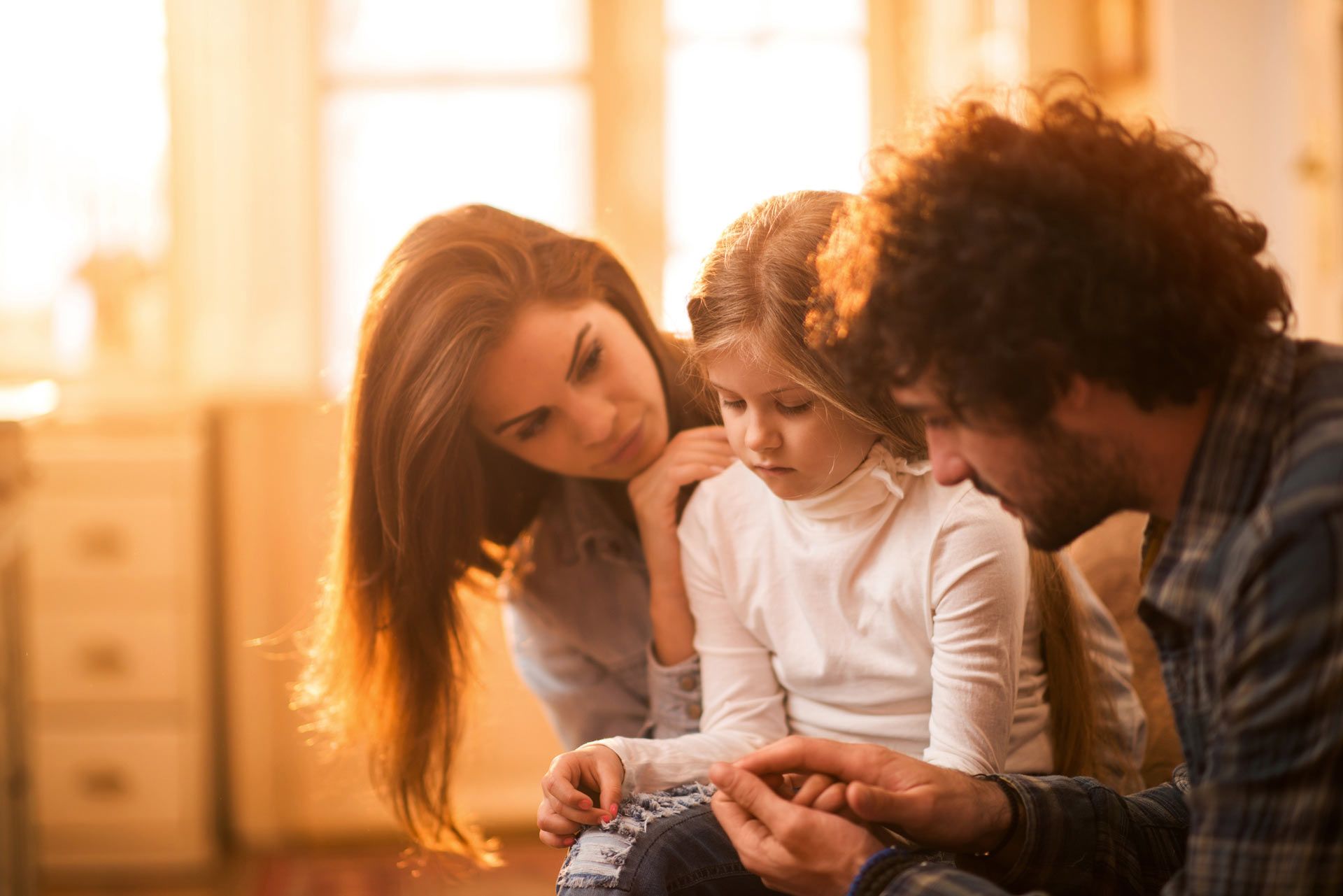A man and woman are sitting on a couch with a little girl