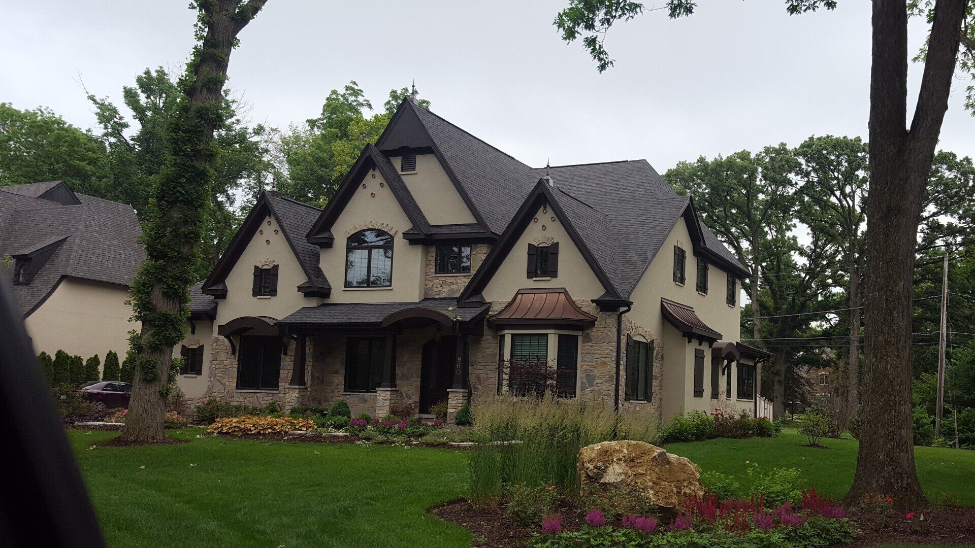 A large house with a black roof is surrounded by trees
