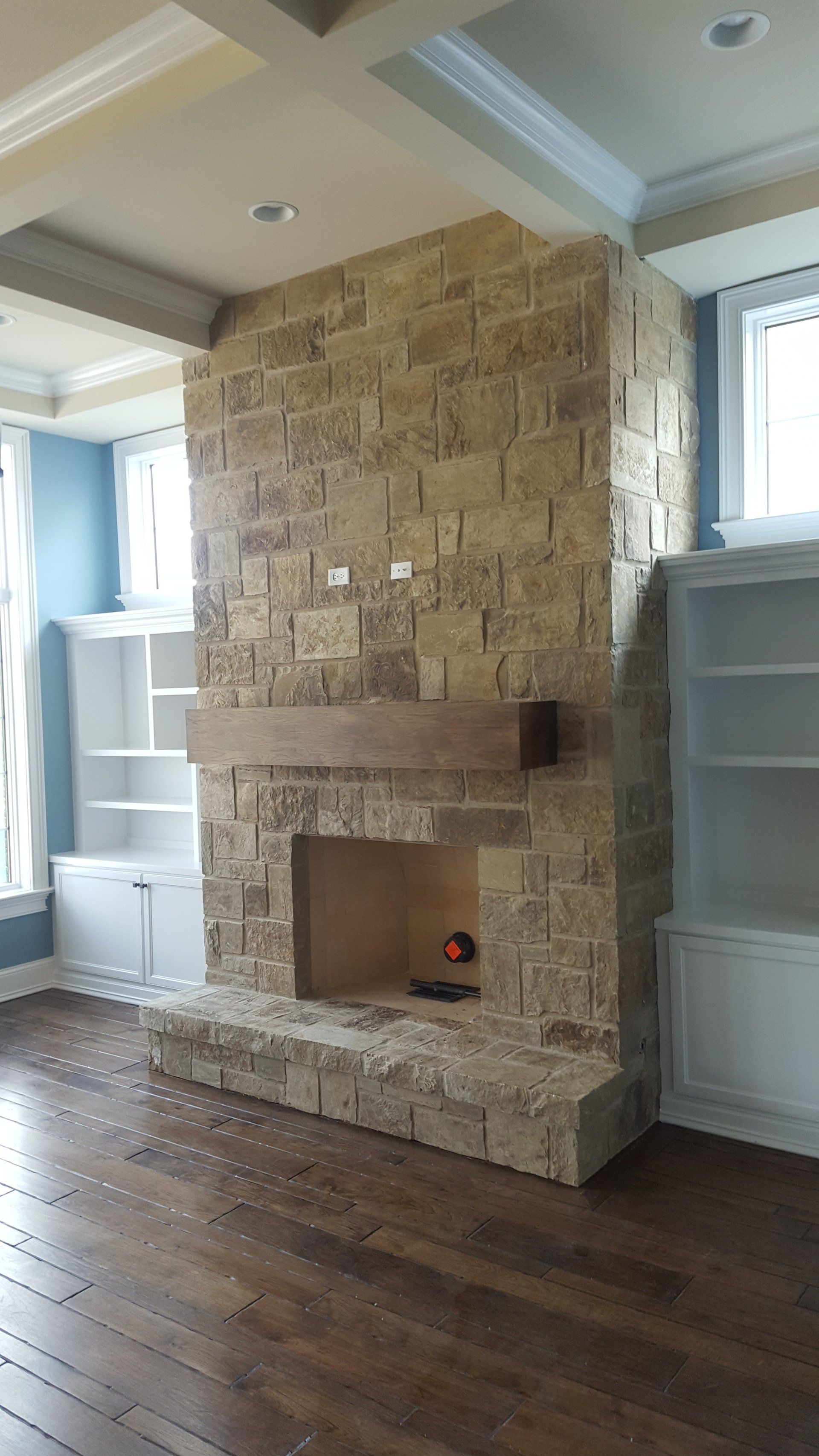 There is a large stone fireplace in the middle of the room.