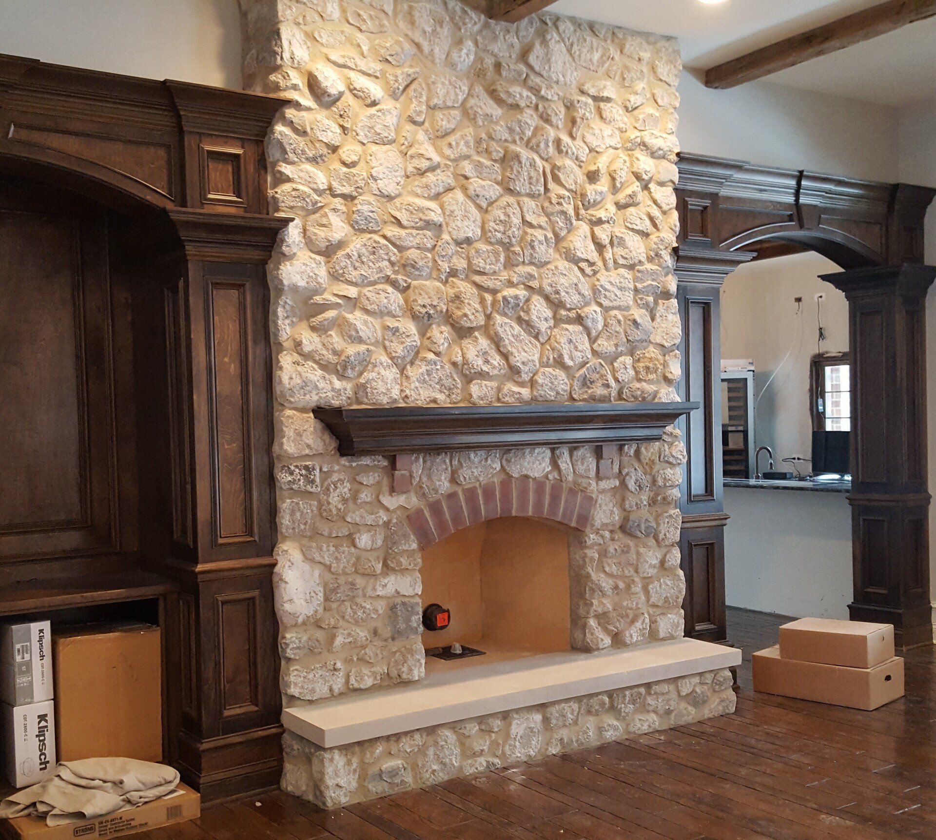 A stone fireplace with a mantle in a living room