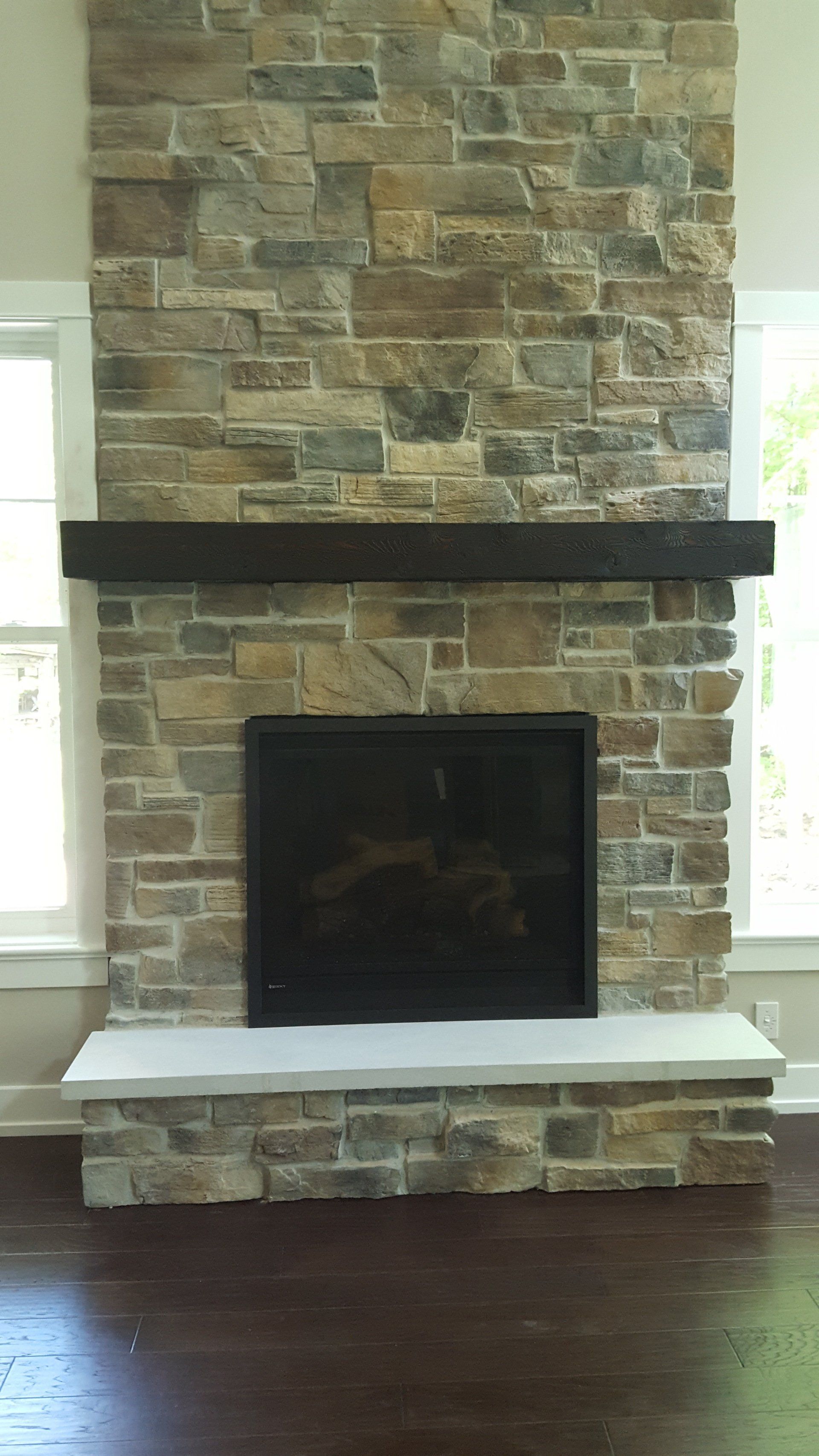 A living room with a stone fireplace and a wooden mantle.