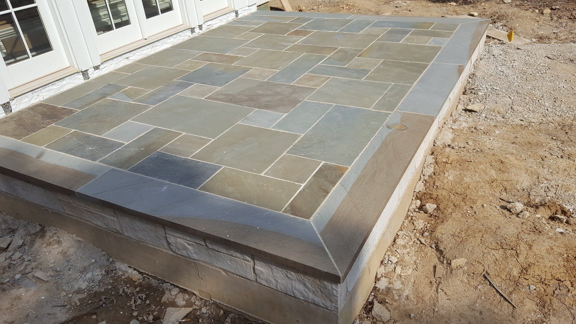 A stone patio is being built in front of a house.