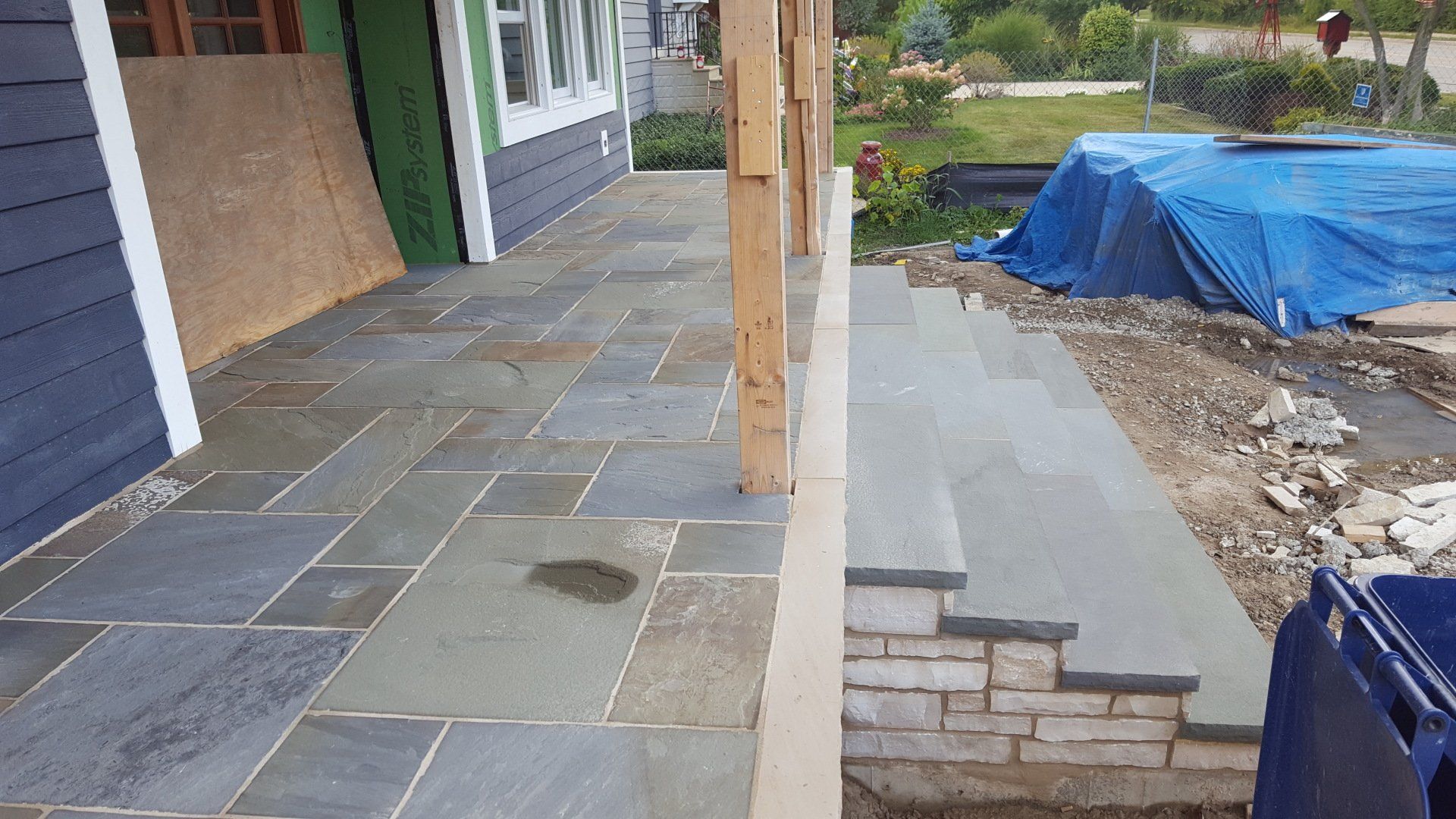 A stone walkway is being built in front of a house.