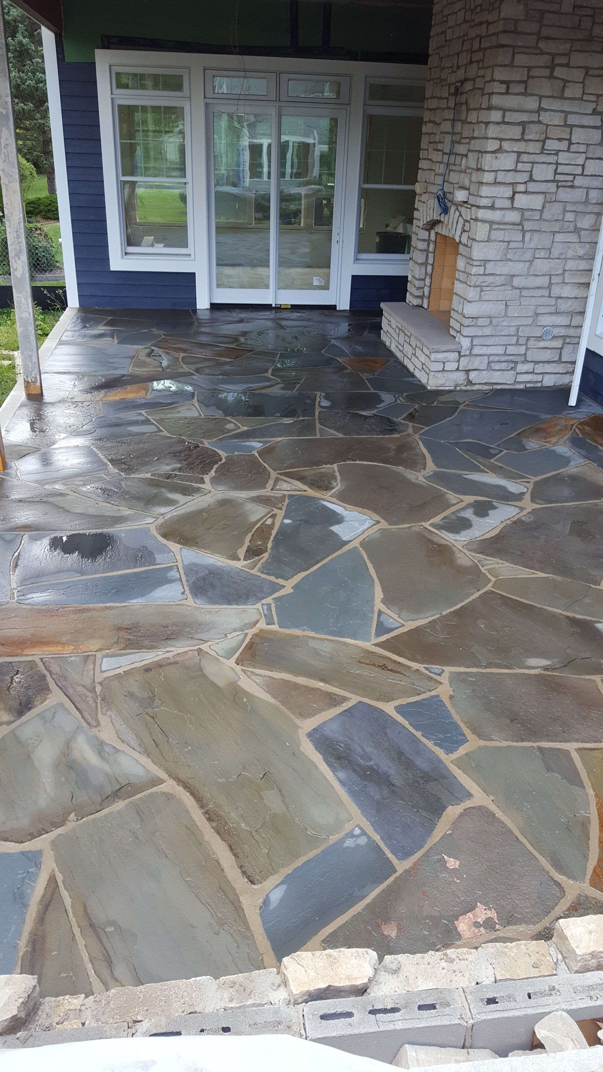 A stone patio is being built in front of a brick house.