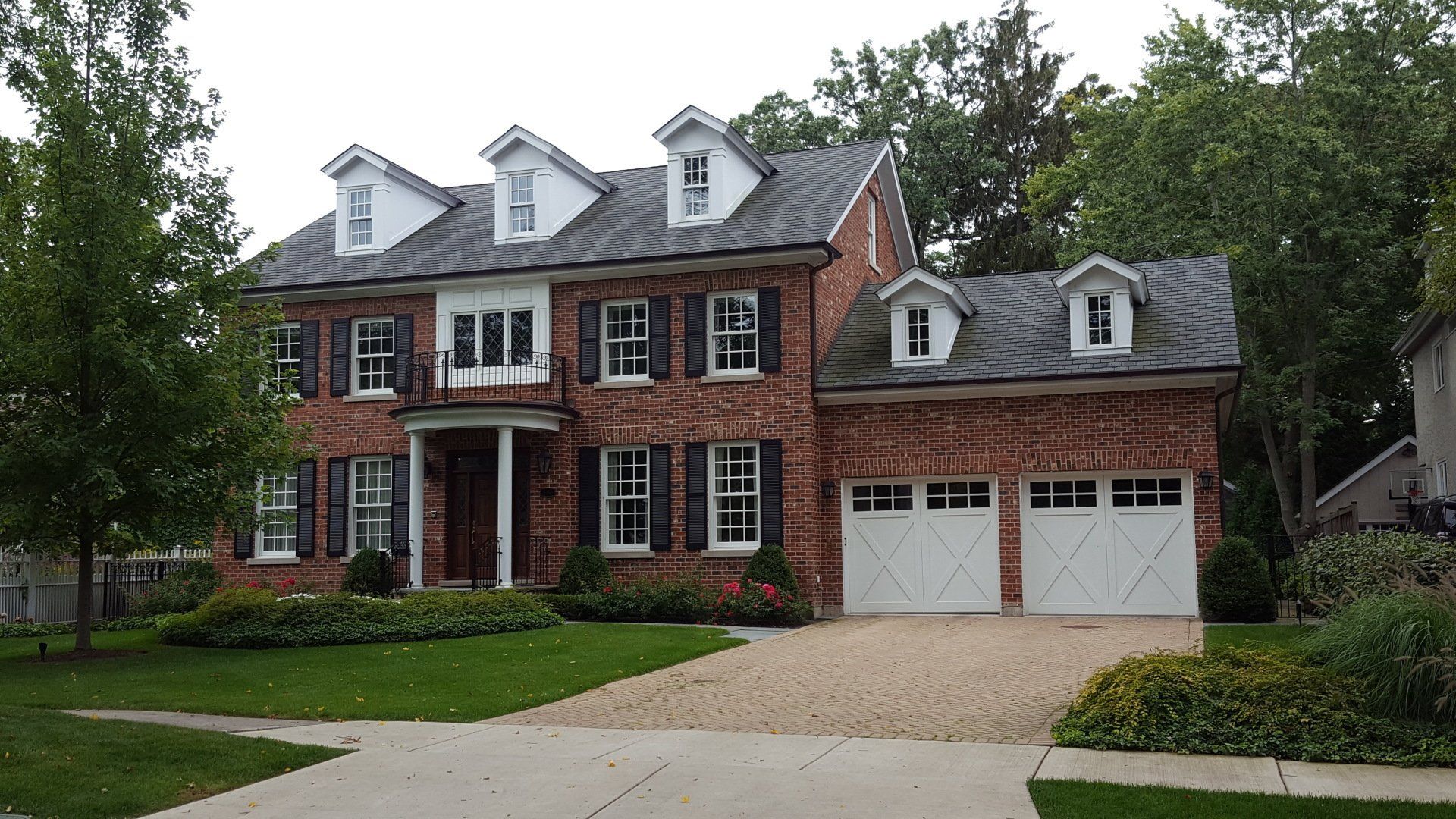 A large brick house with white garage doors and shutters