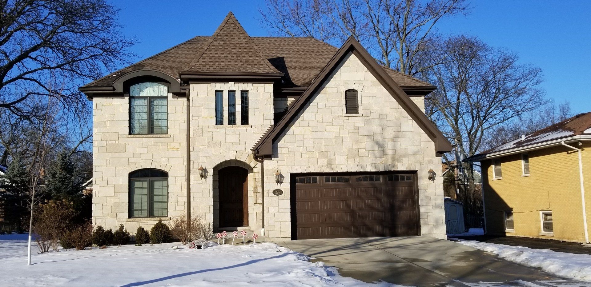 A large house with a garage and a driveway covered in snow.