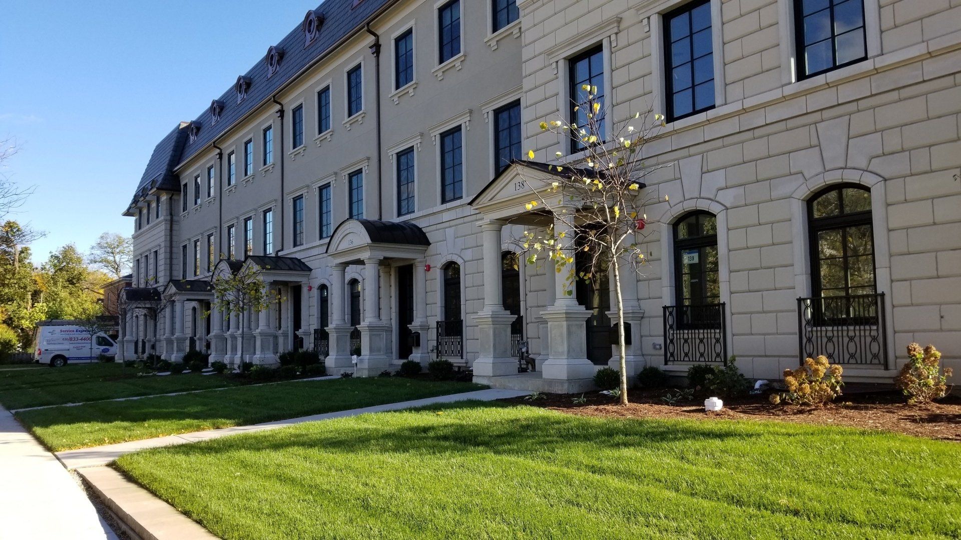 A large building with a lot of windows and a lush green lawn in front of it.