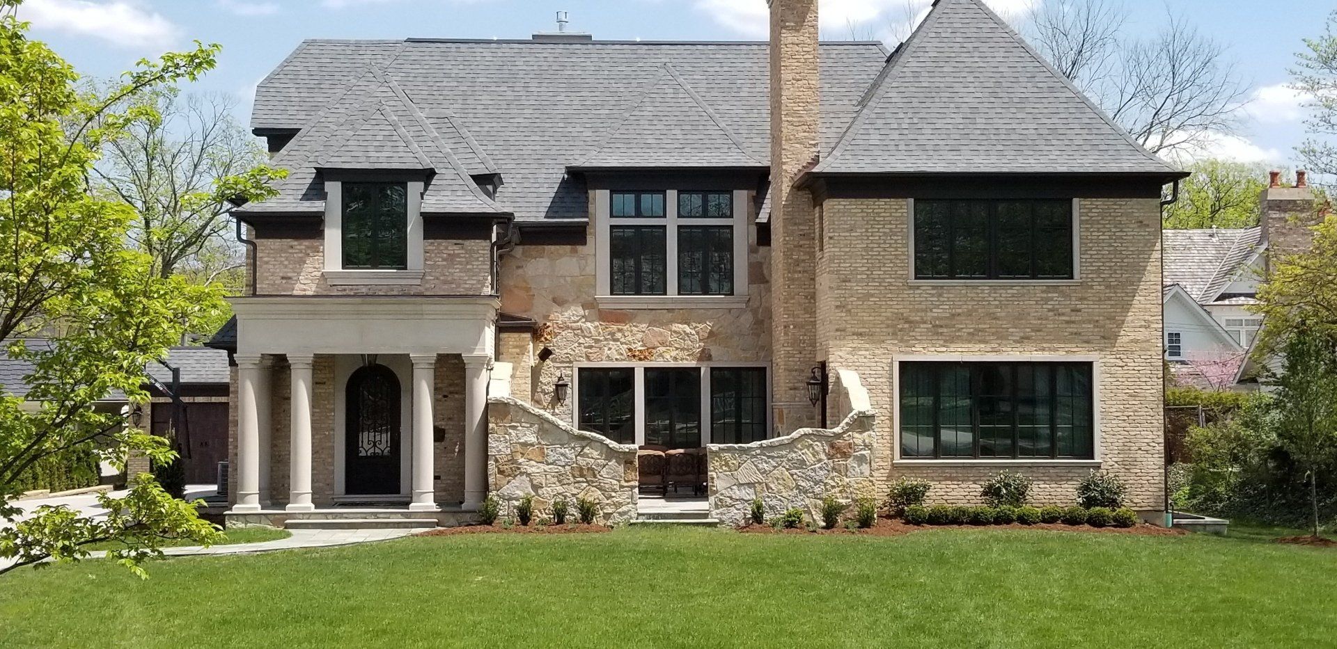 A large brick house with a large lawn in front of it