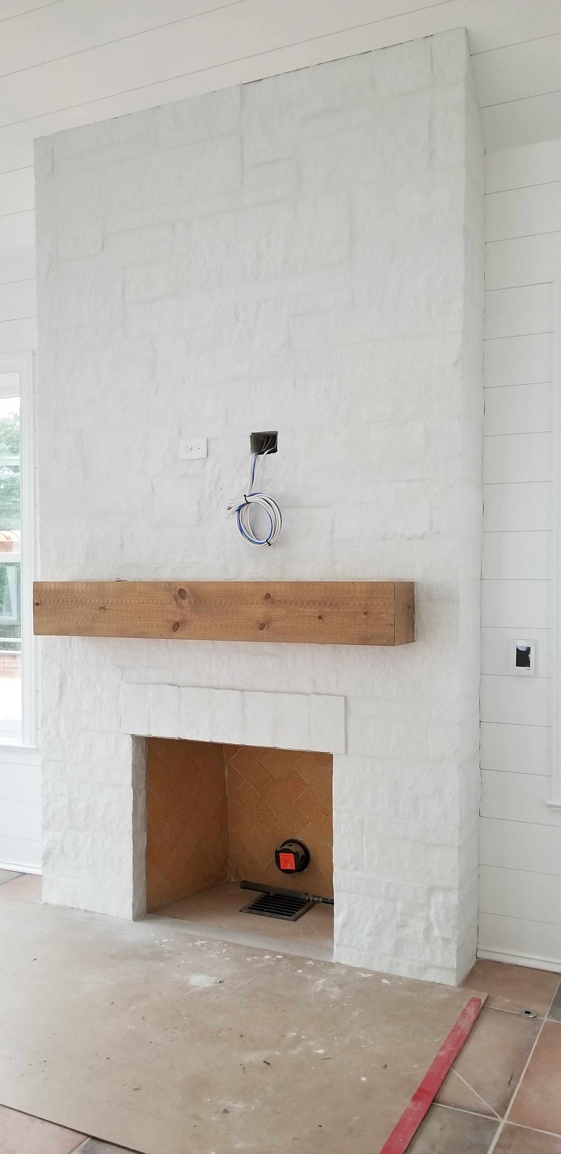 A white fireplace with a wooden mantle in a living room.