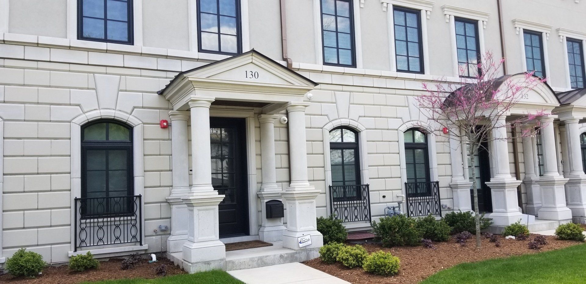 A large white building with black windows and a porch.
