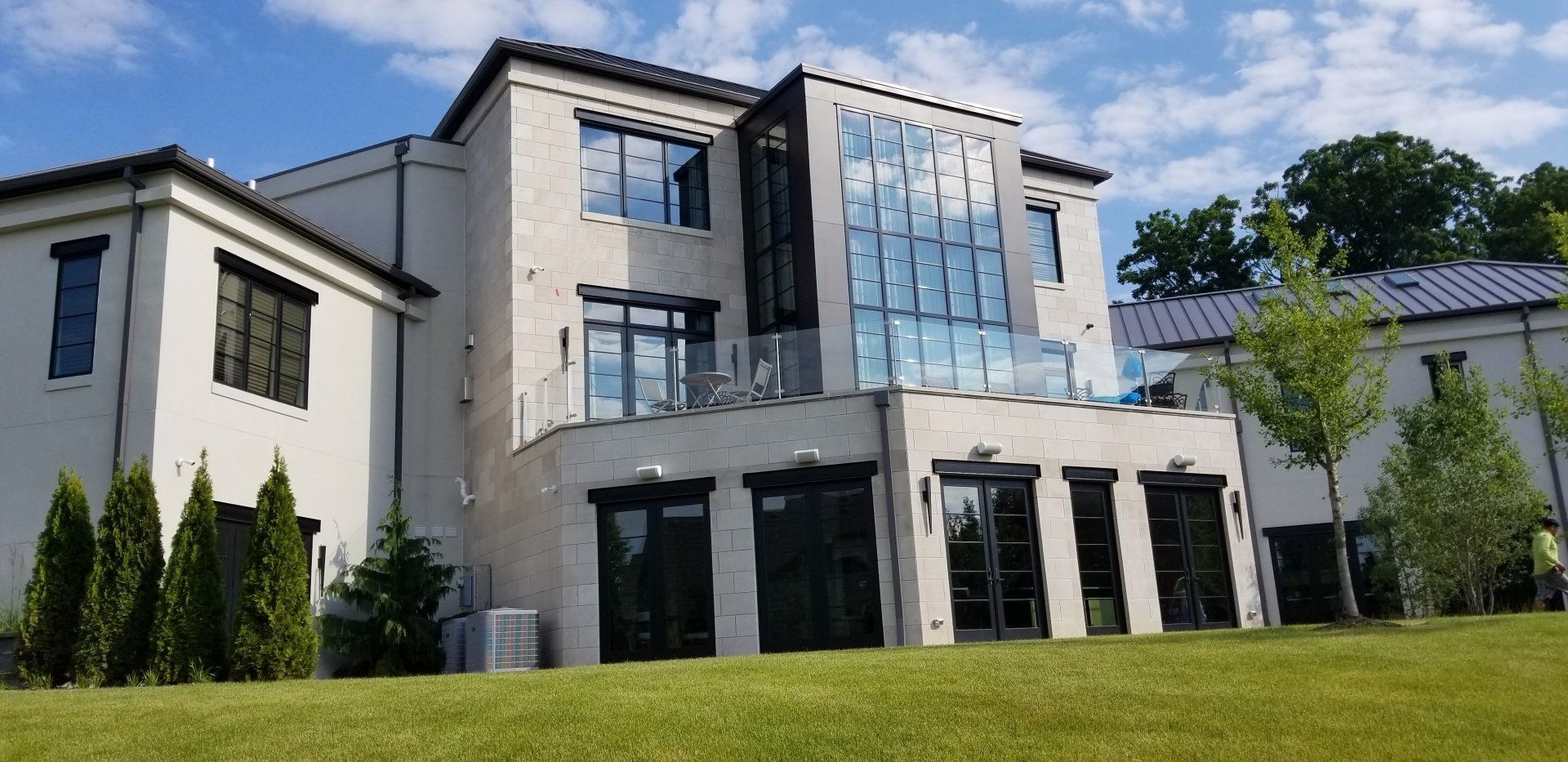A large white house with a lot of windows is sitting on top of a lush green hill.