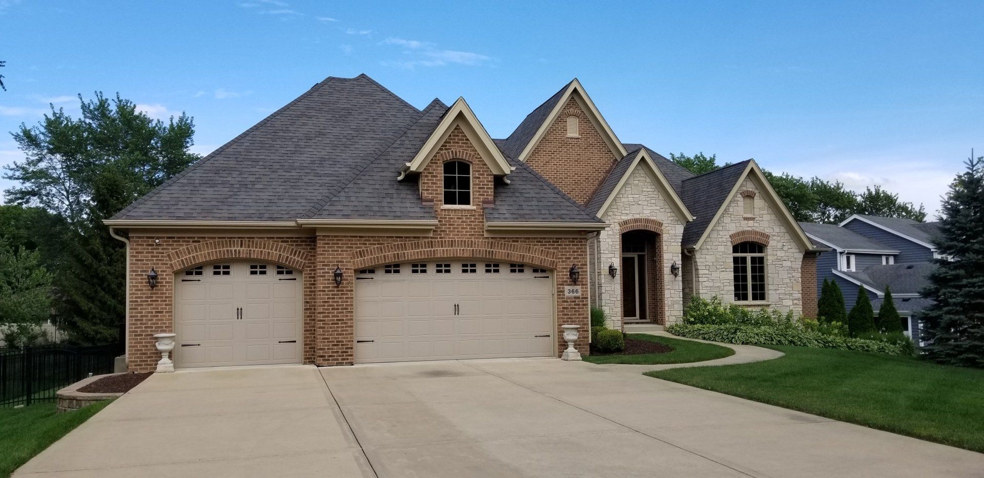 A large brick house with two garage doors and a driveway