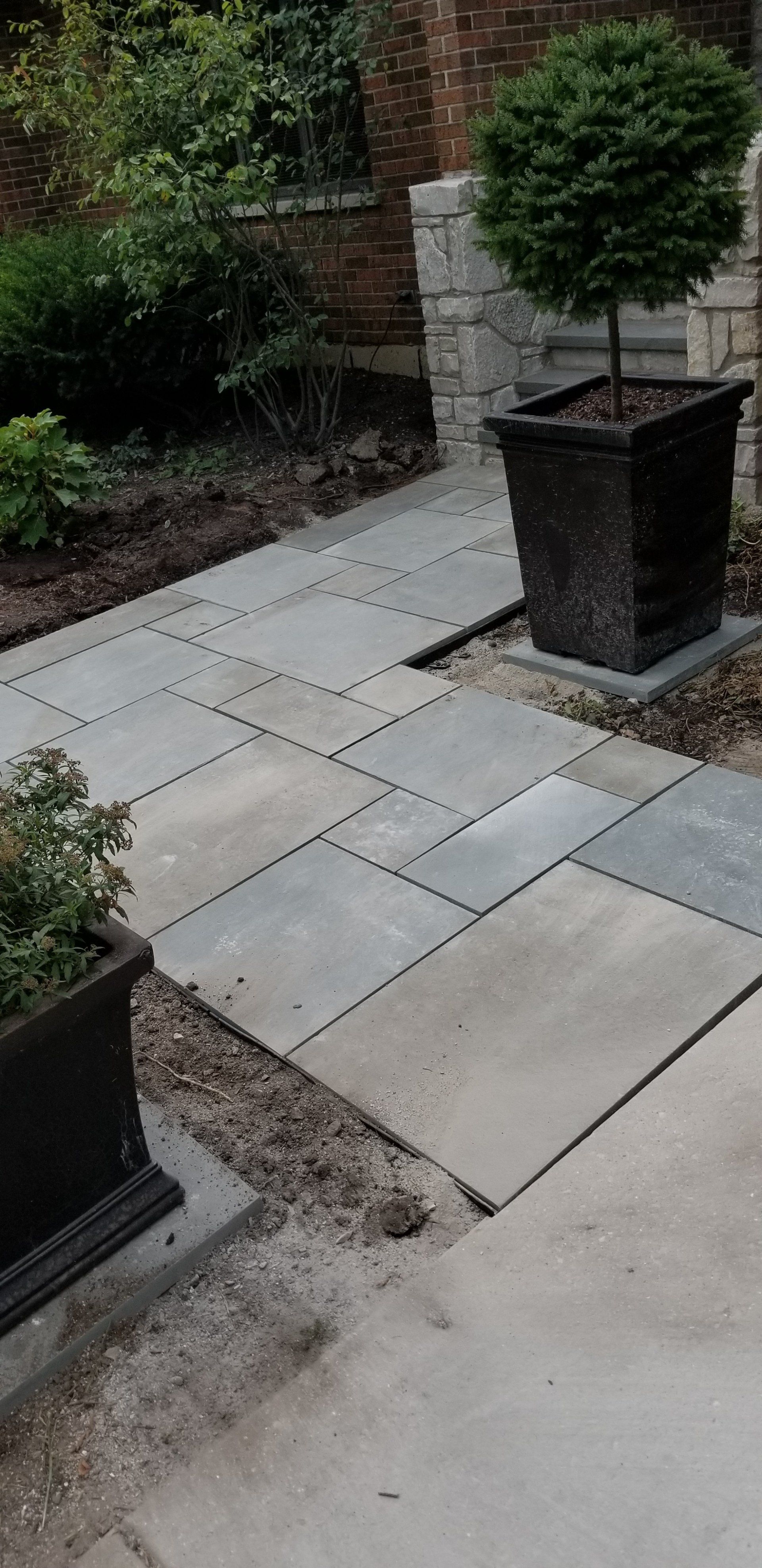 A stone walkway with potted plants on the side of it.