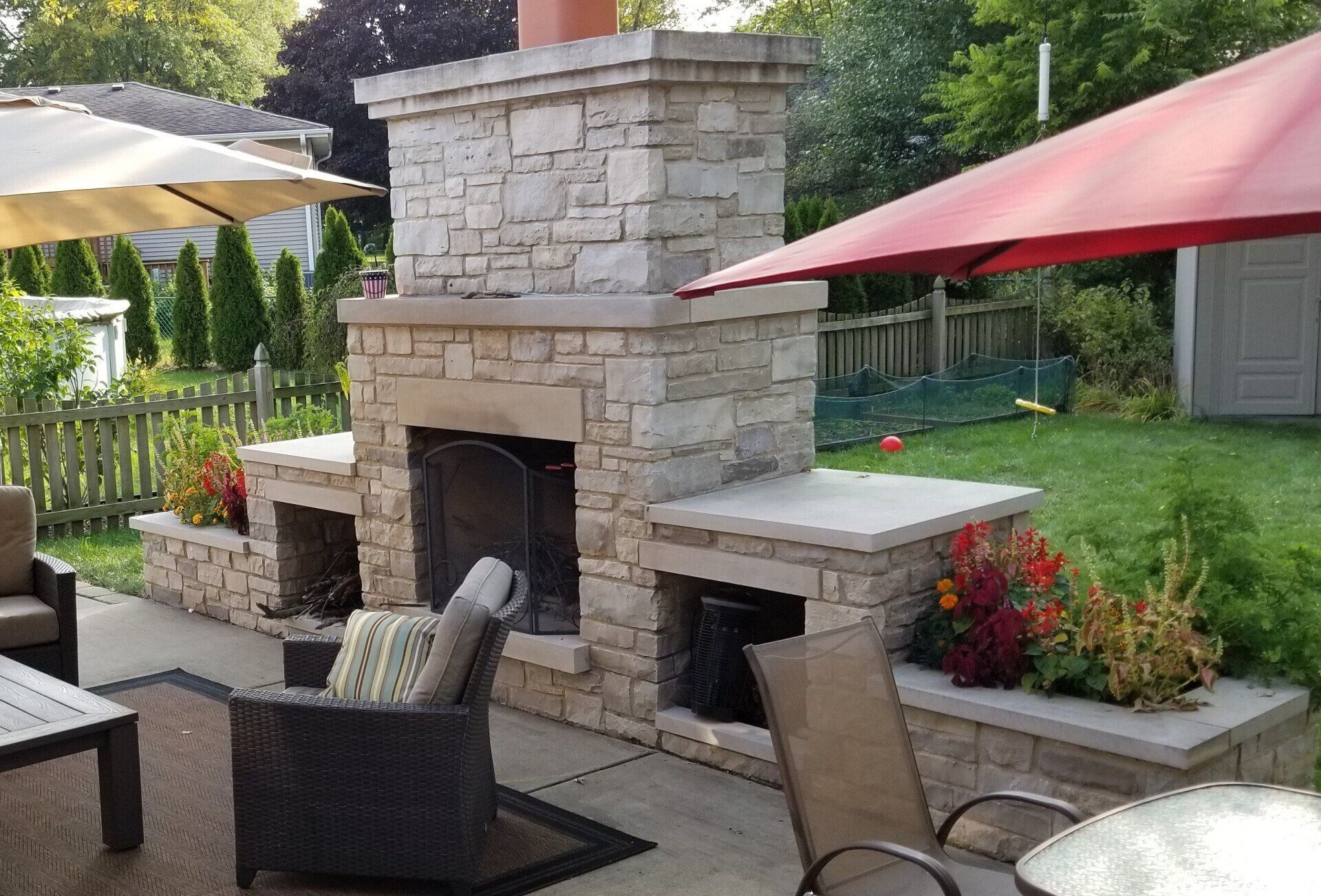 A patio with a fireplace and chairs and umbrellas