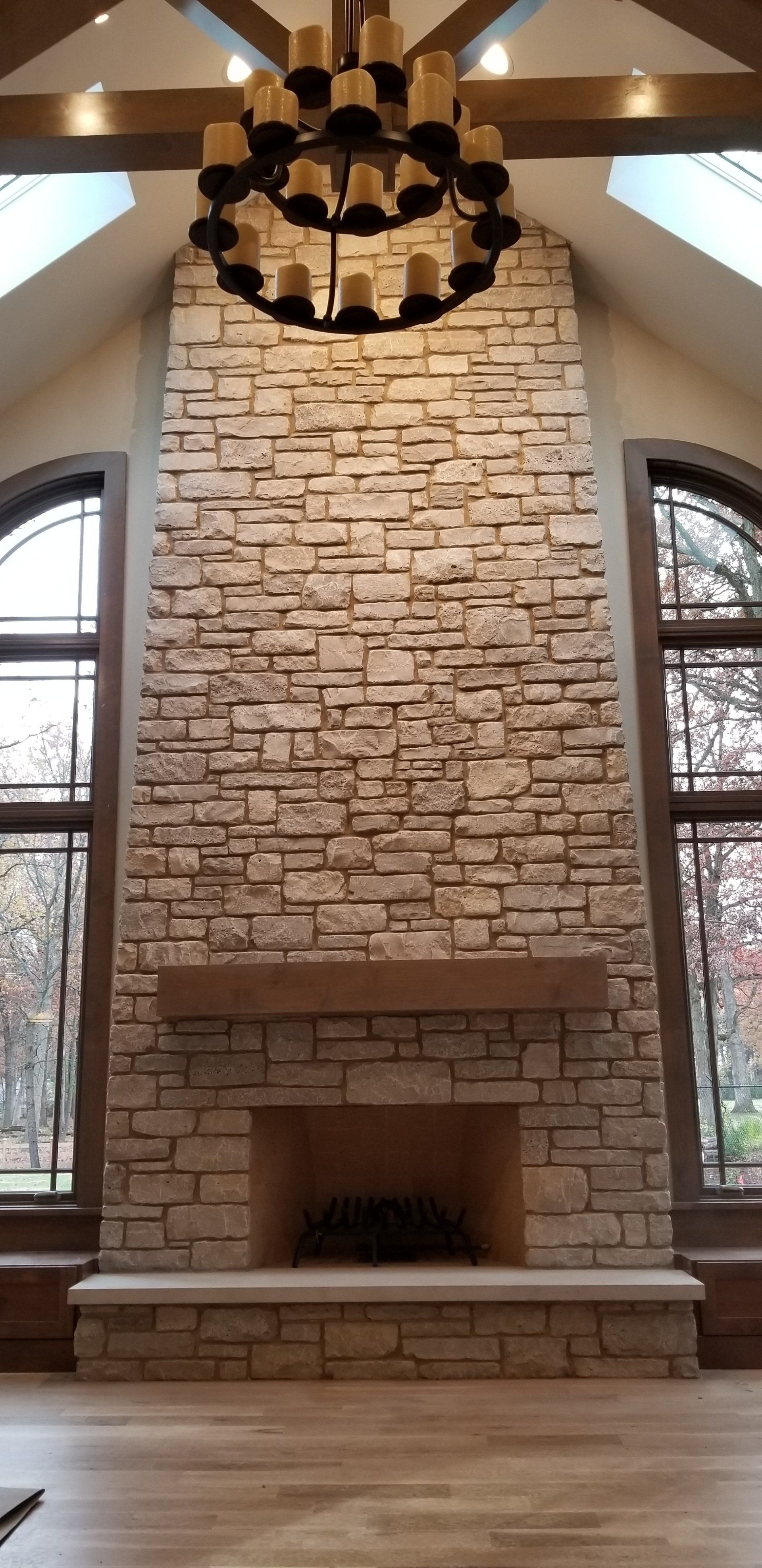 A large brick fireplace in a living room with a chandelier hanging from the ceiling.