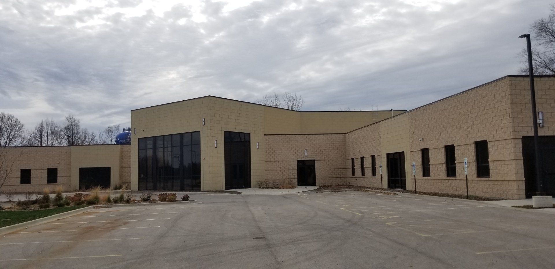 A large building with a lot of windows is sitting in a parking lot.