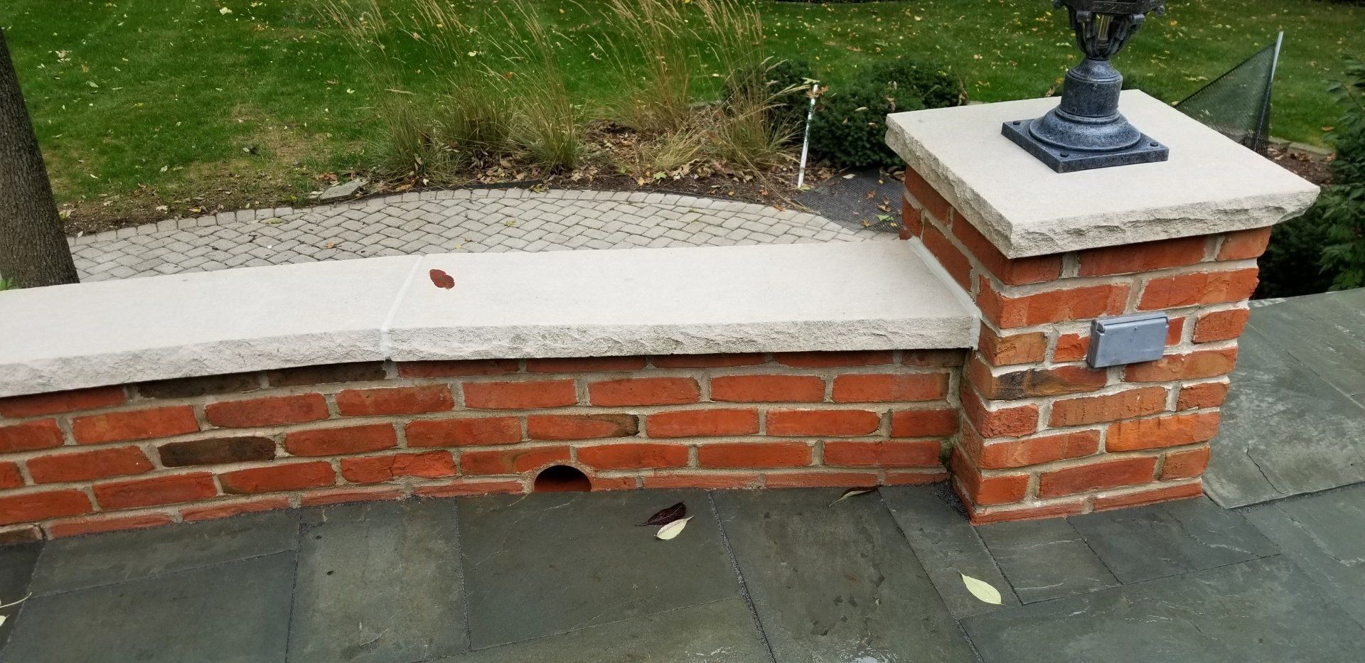 A brick wall with a planter on top of it.