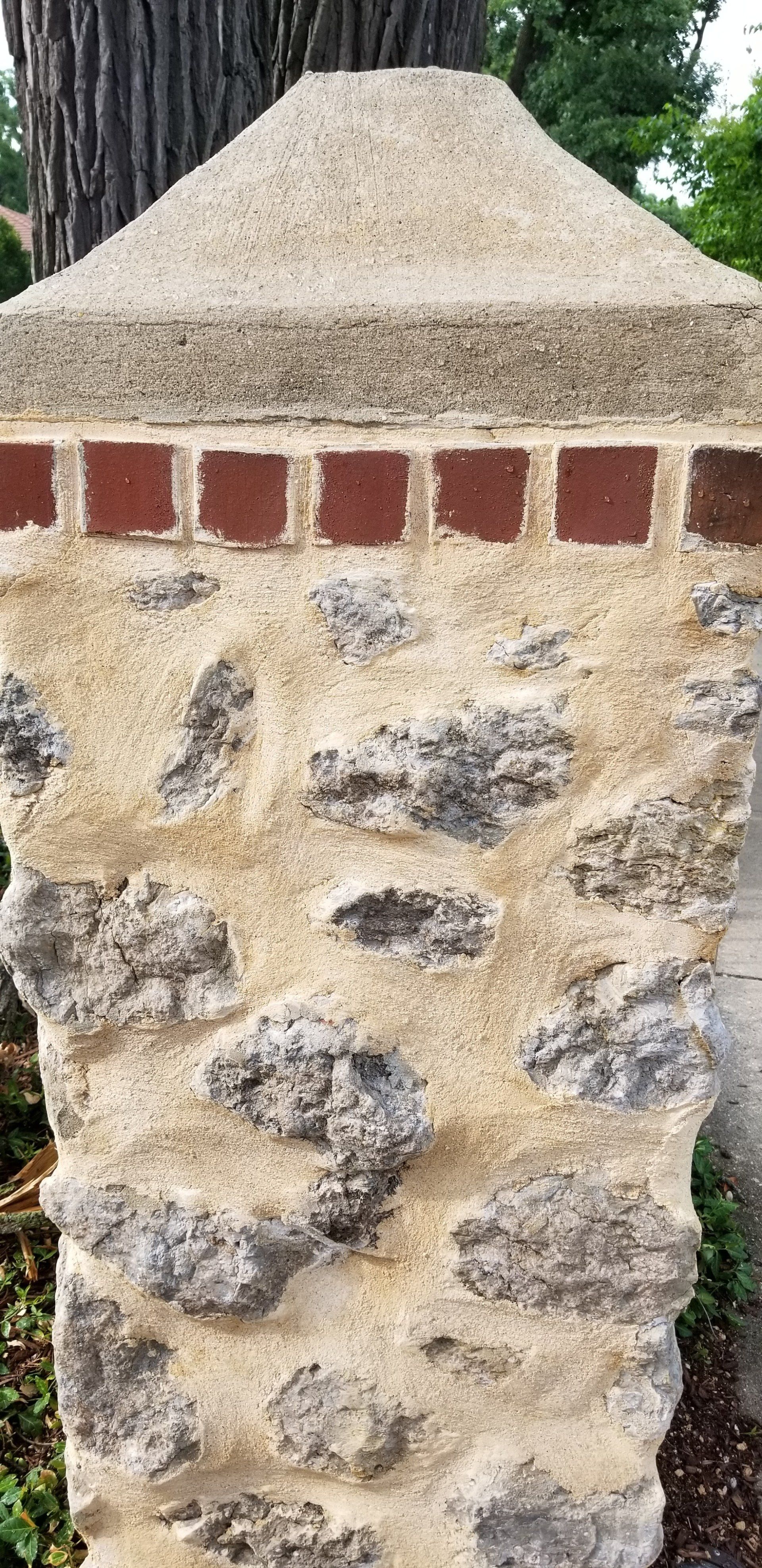 A close up of a stone wall with a tree in the background.