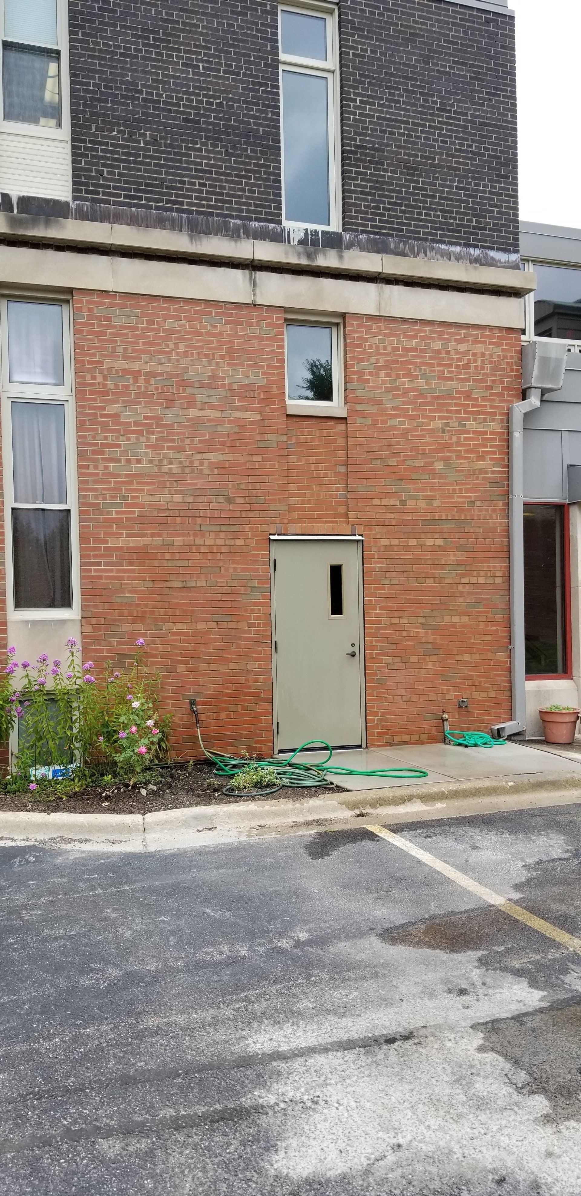 A brick building with a door and a window in a parking lot.